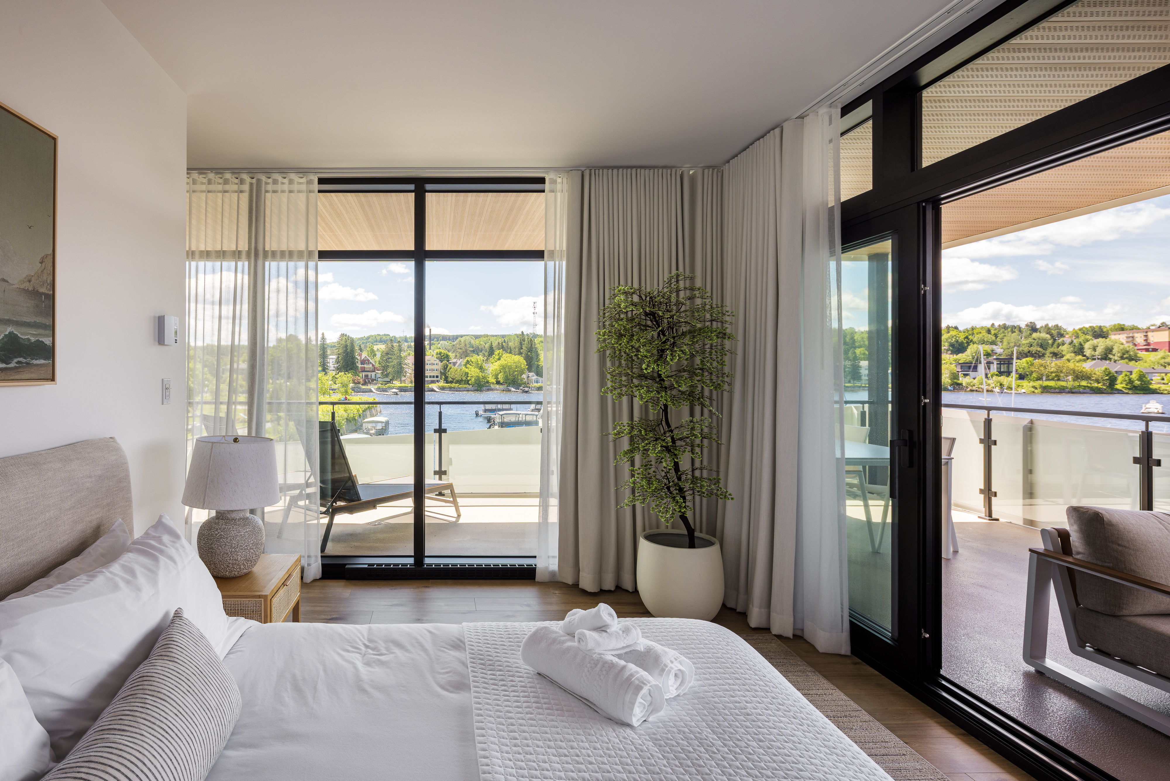 Photographie architecturale d'une chambre avec porte-fenêtre, lumière naturelle et vue sur le lac Mégantic