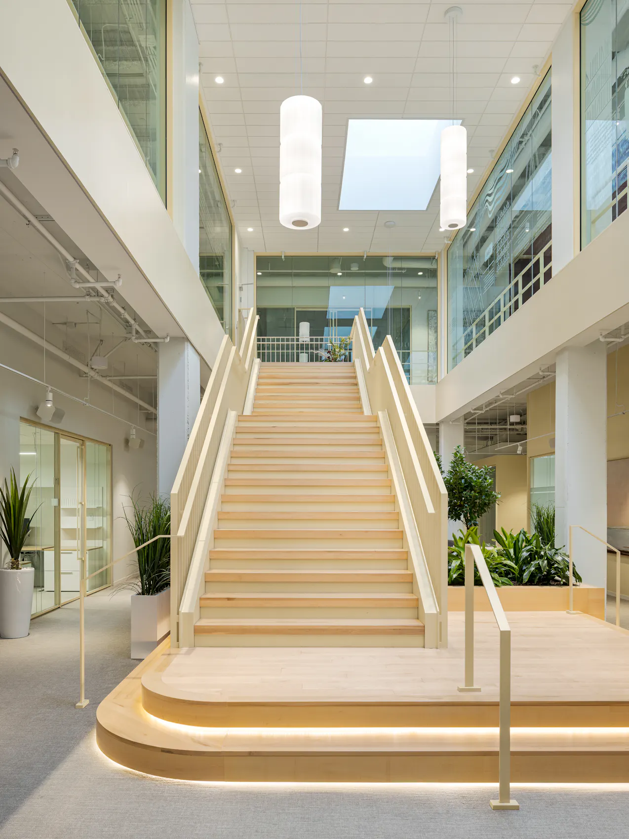 Escalier architectural en bois au cœur d’un espace de travail lumineux et moderne.