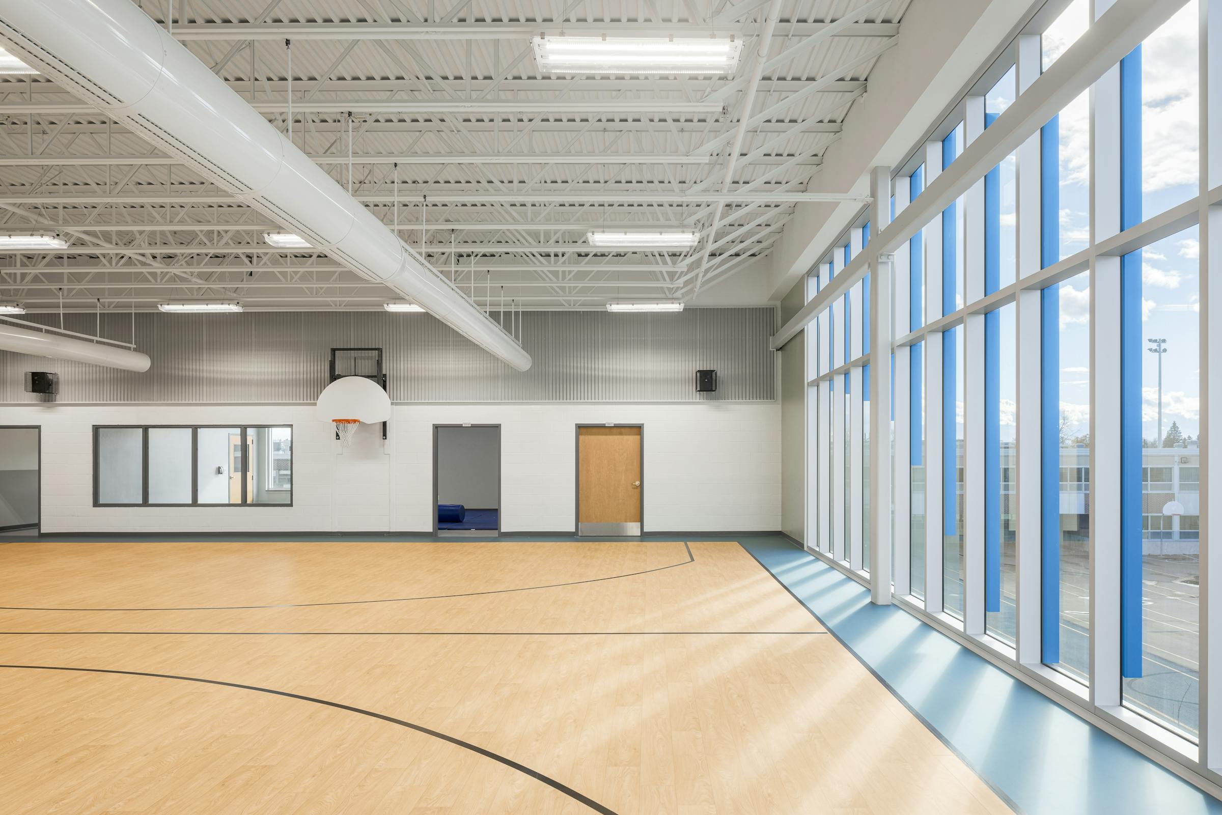 Vue d’ensemble du gymnase scolaire captée en photographie d’architecture, mettant en valeur la lumière naturelle et les matériaux durables.
