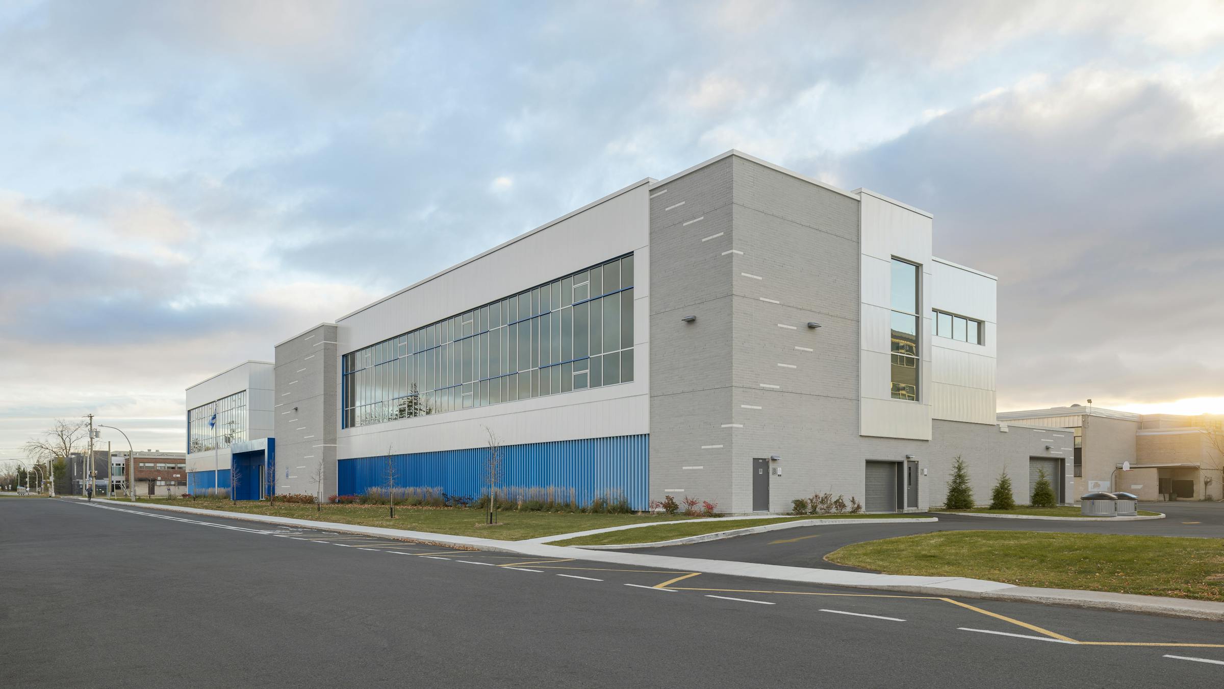 Vue d’ensemble du bâtiment scolaire avec ses volumes clairs, ses lignes simples et ses touches de bleu intégrées au design.