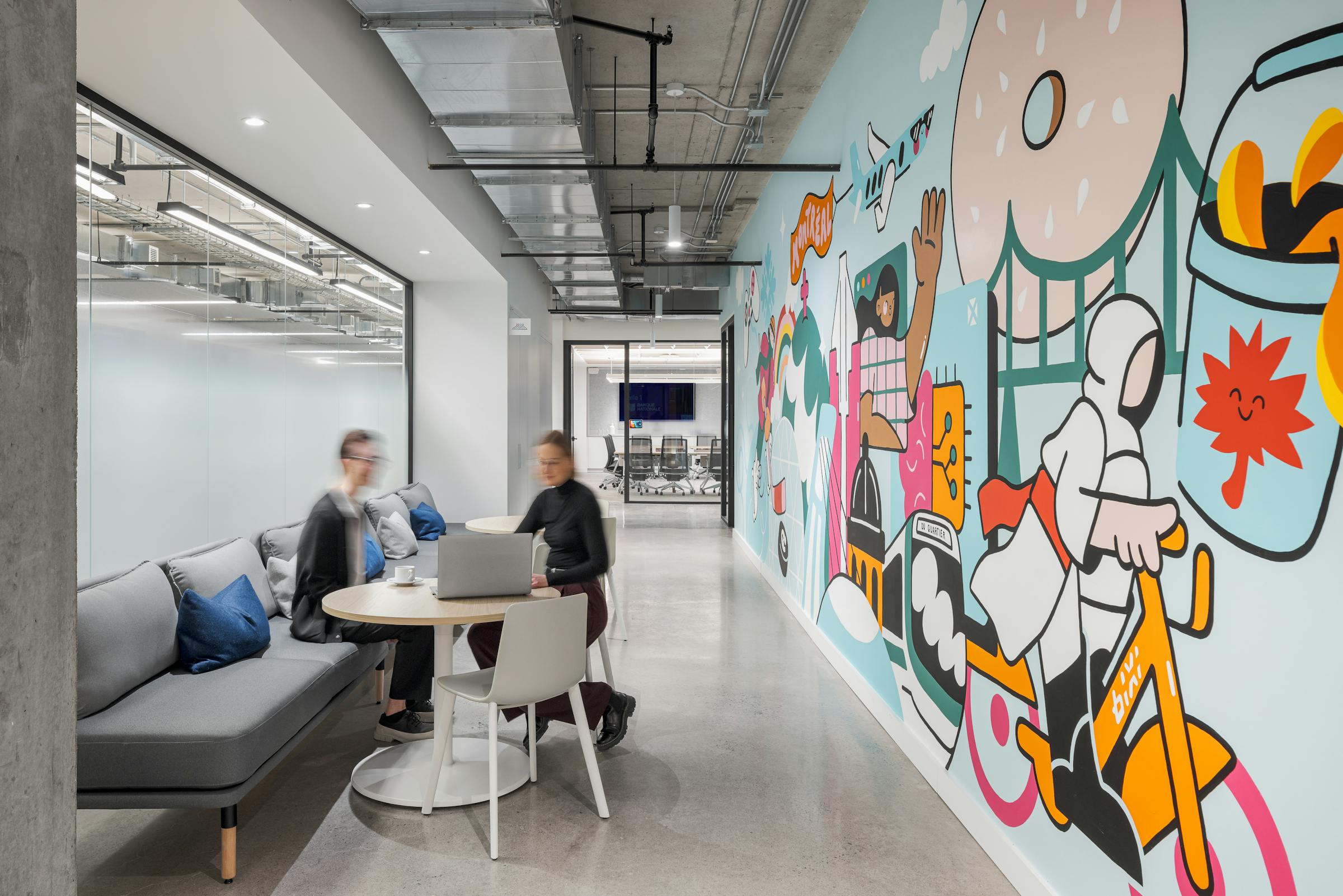 Espace collaboratif dans un couloir et murale coloré inspiré de la ville de Montréal.