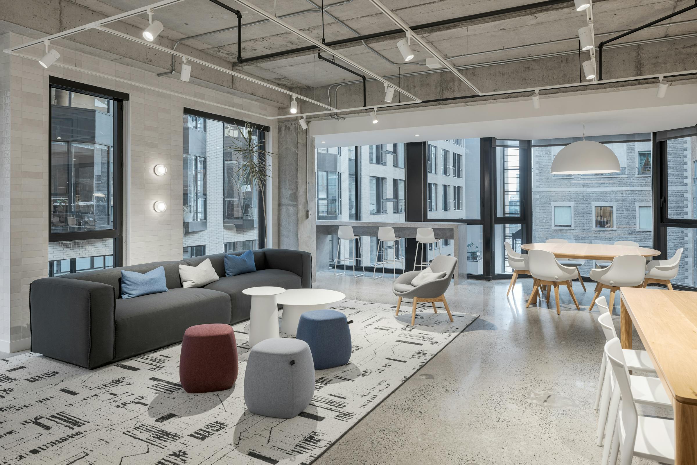 Salle de détente avec design intérieur confortable : canapés, table basse et vue panoramique à travers des murs architecturaux en verre.