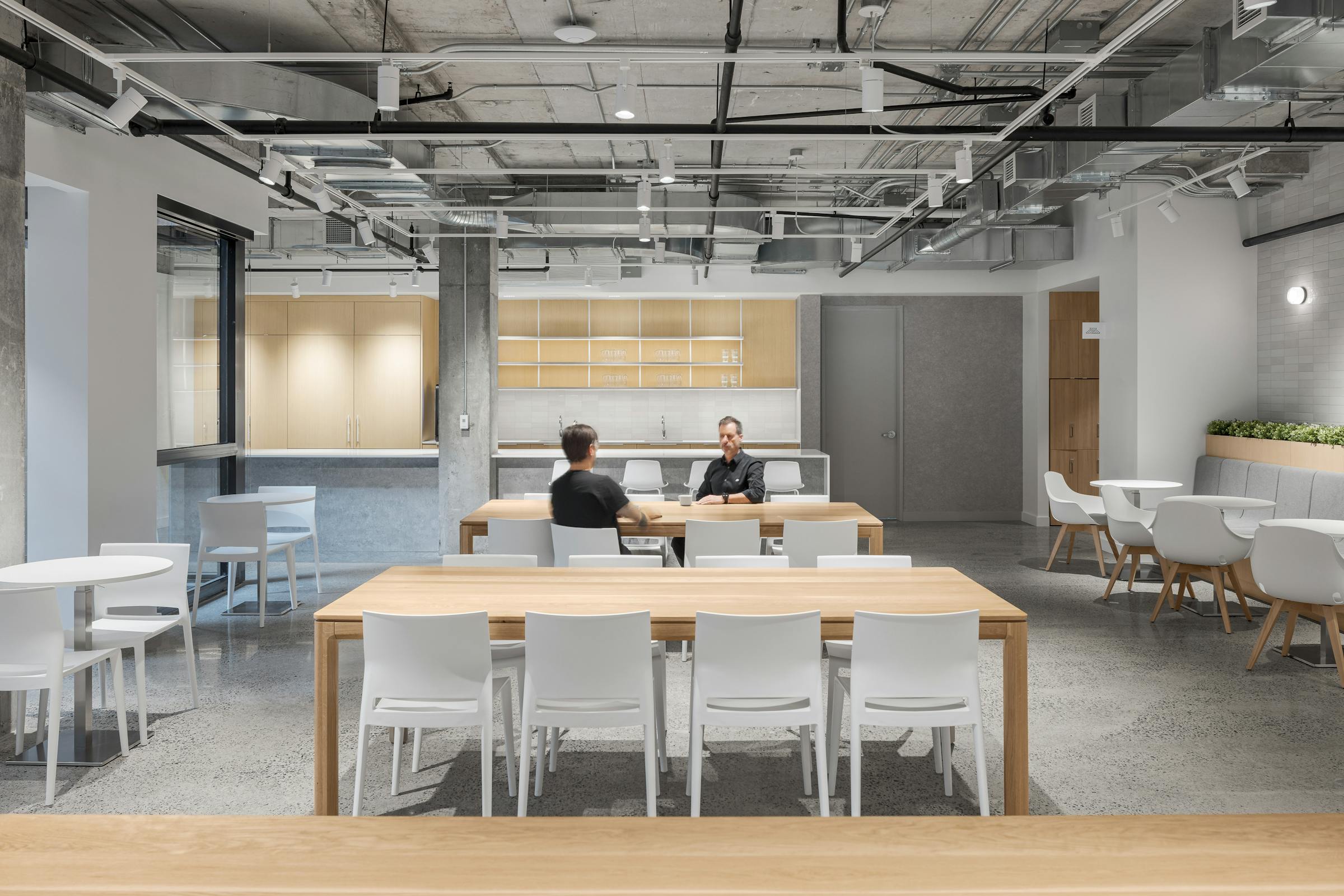 Design intérieur de cuisine d'entreprise : îlot central, tabourets hauts et appareils modernes intégrés dans une architecture ouverte.