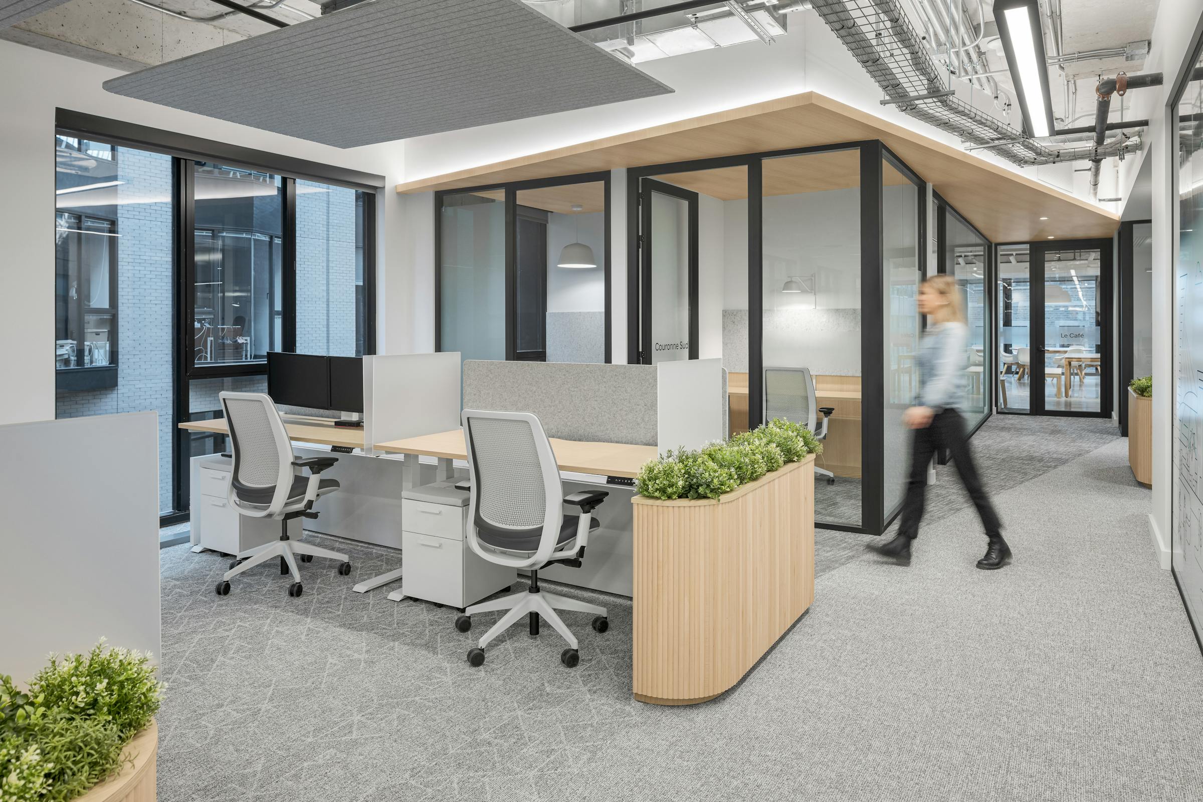 Espace de travail ouvert avec architecture de cloisons en verre, postes individuels et design intérieur axé sur la luminosité.