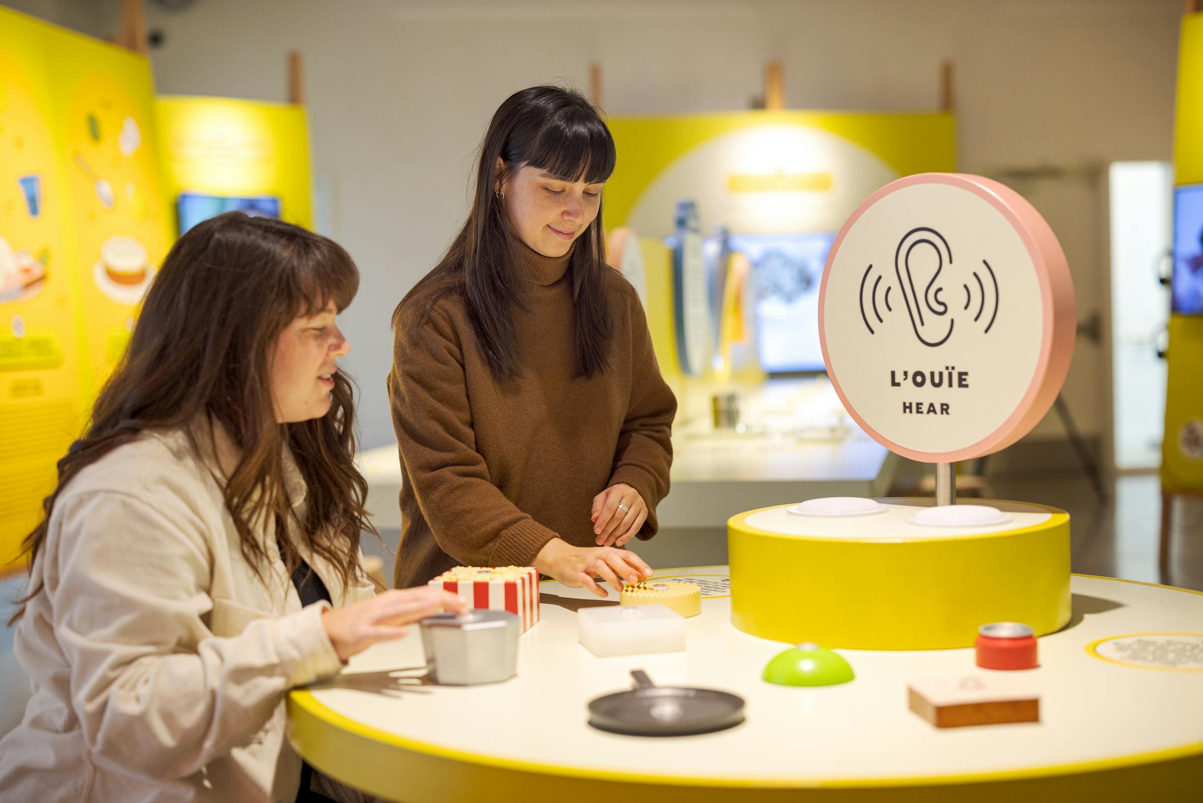 Two visitors interact with a video screen in an educational exhibit about food and its impact.