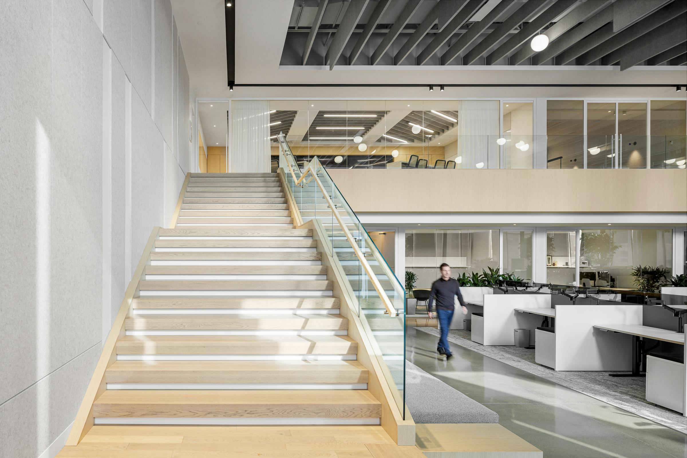A large architectural staircase connecting the floor and the mezzanine in modern designed work spaces.