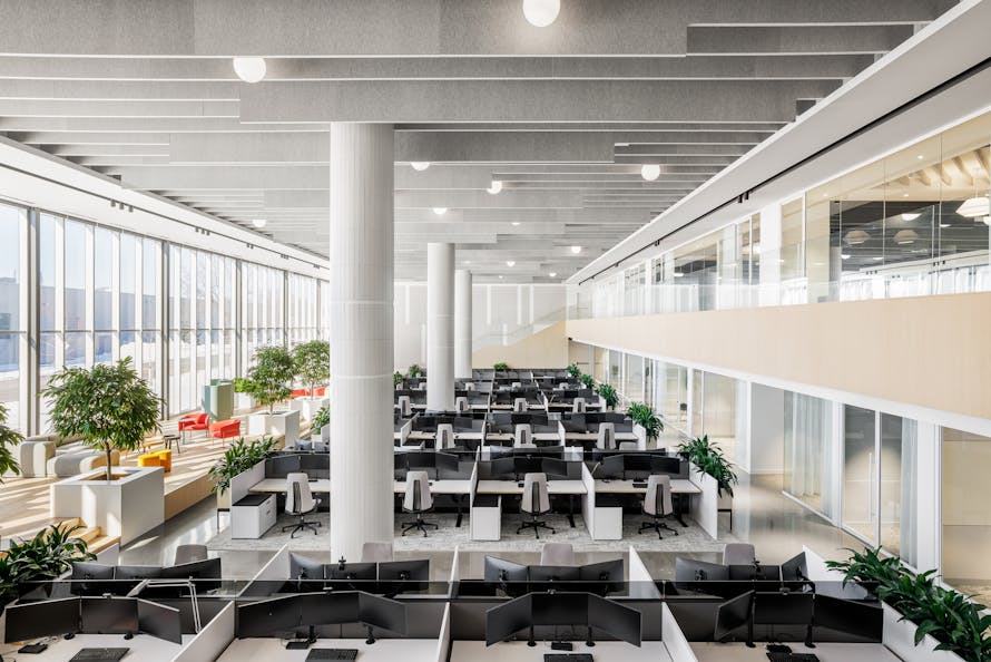 Wide angle and overhead view of a large room with a multitude of workstations.