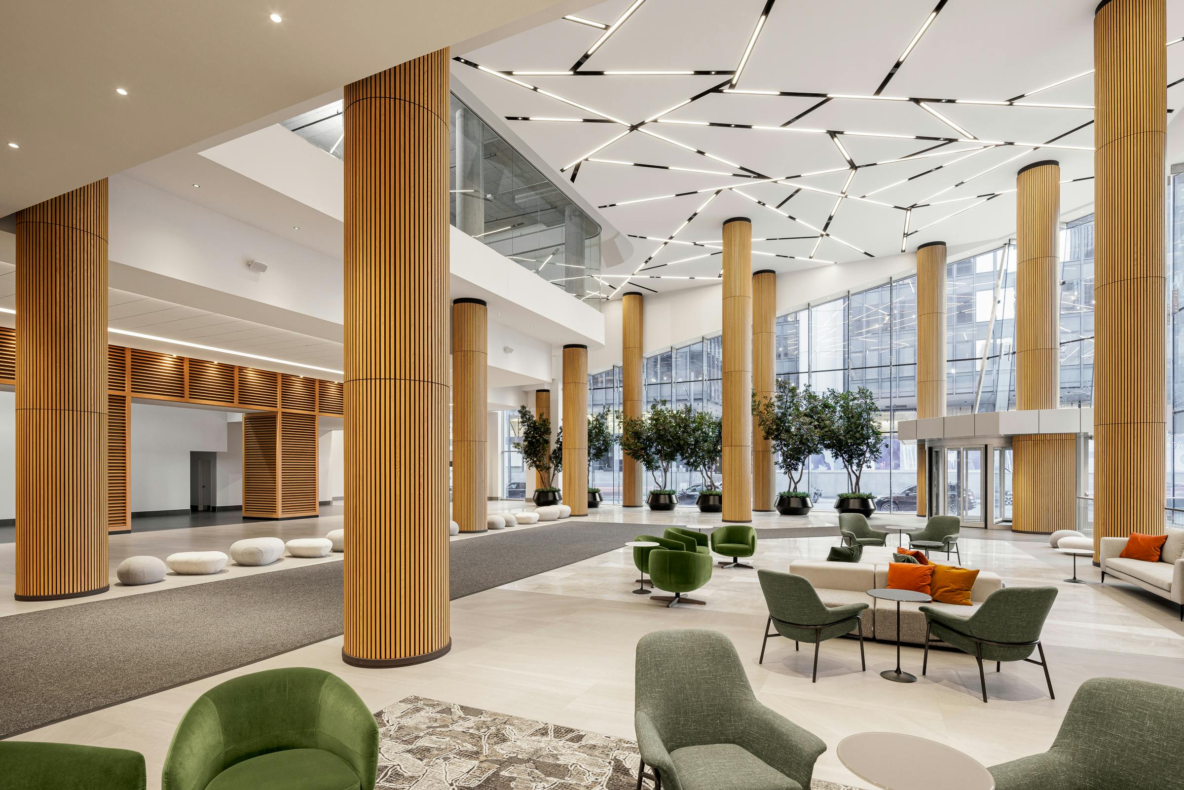 Large lobby au design et au volume impressionnant avec du mobilier coloré et des colonnes avec un revêtement en bois.