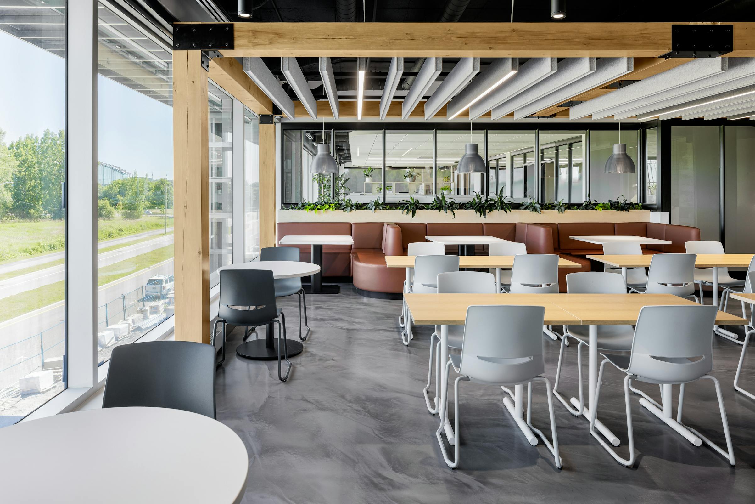 Cafétéria au sol en béton ciré et poutres apparentes au design et à l'architecture industriel.