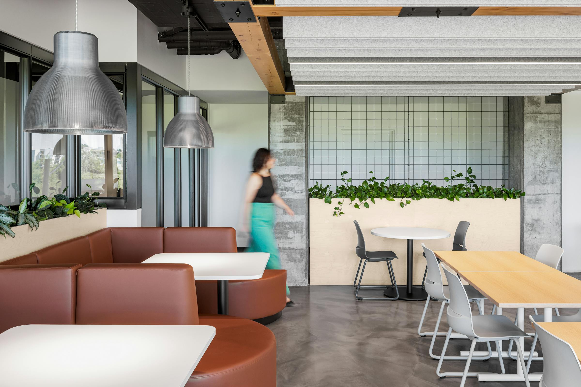 Salle de pause conviviale avec banquettes en cuir et tables modernes.