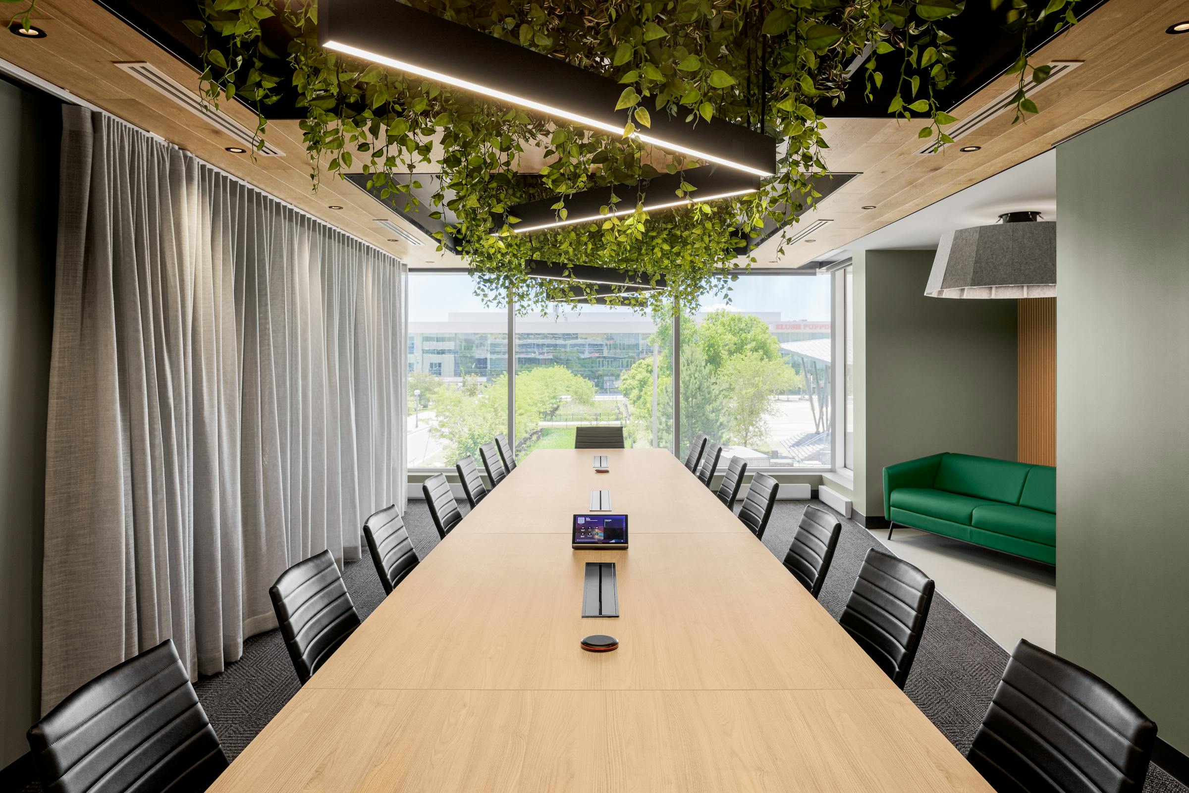Salle de réunion minimaliste avec une table centrale et un plafond vegetal.