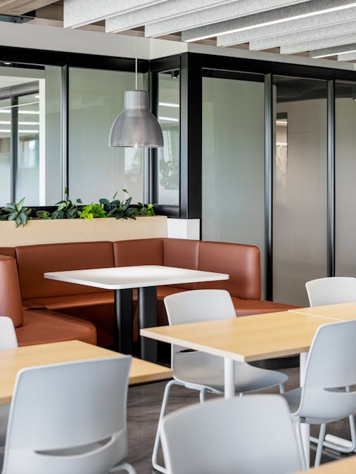 Cafétéria lumineuse avec des poutres en bois et de grandes baies vitrées.