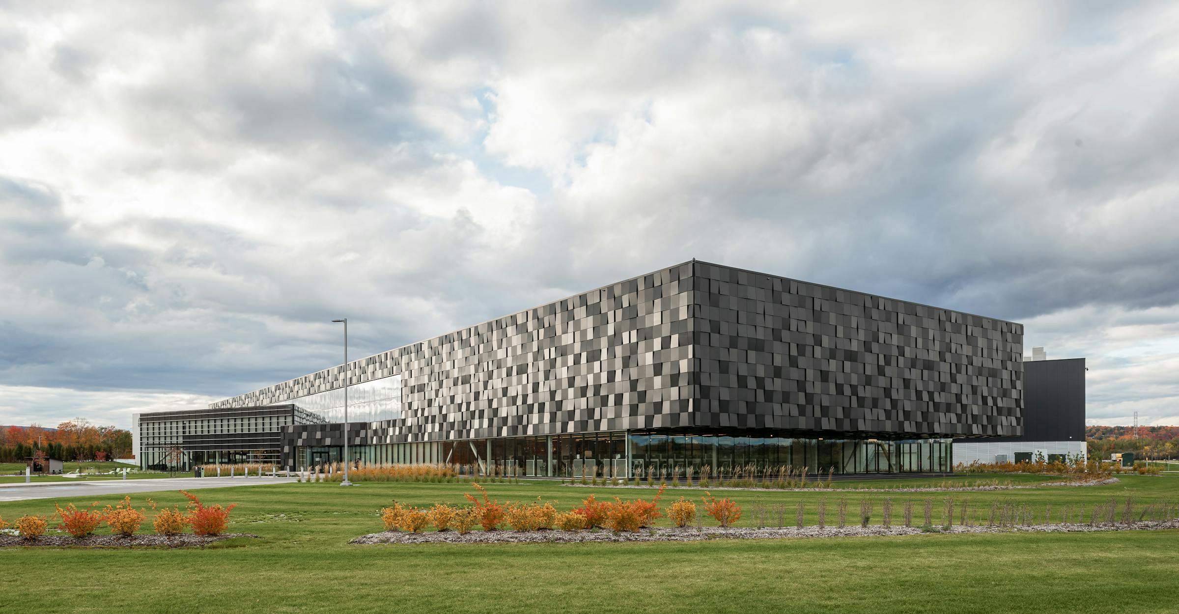 Photograph of the architecture of a very large commercial distribution center in Quebec. The facets of the facade reflect natural light.