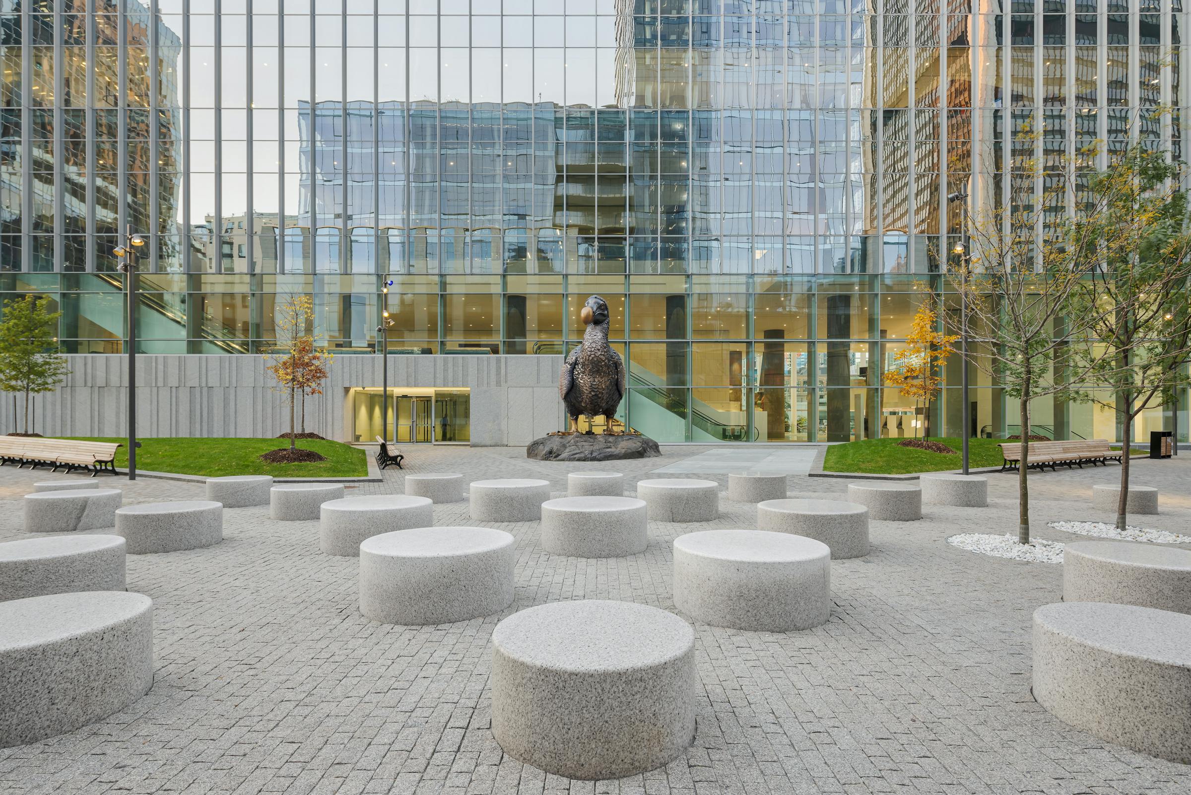 Perspective rasante montrant des assises circulaires en pierre claire sous les arbres du parc.
