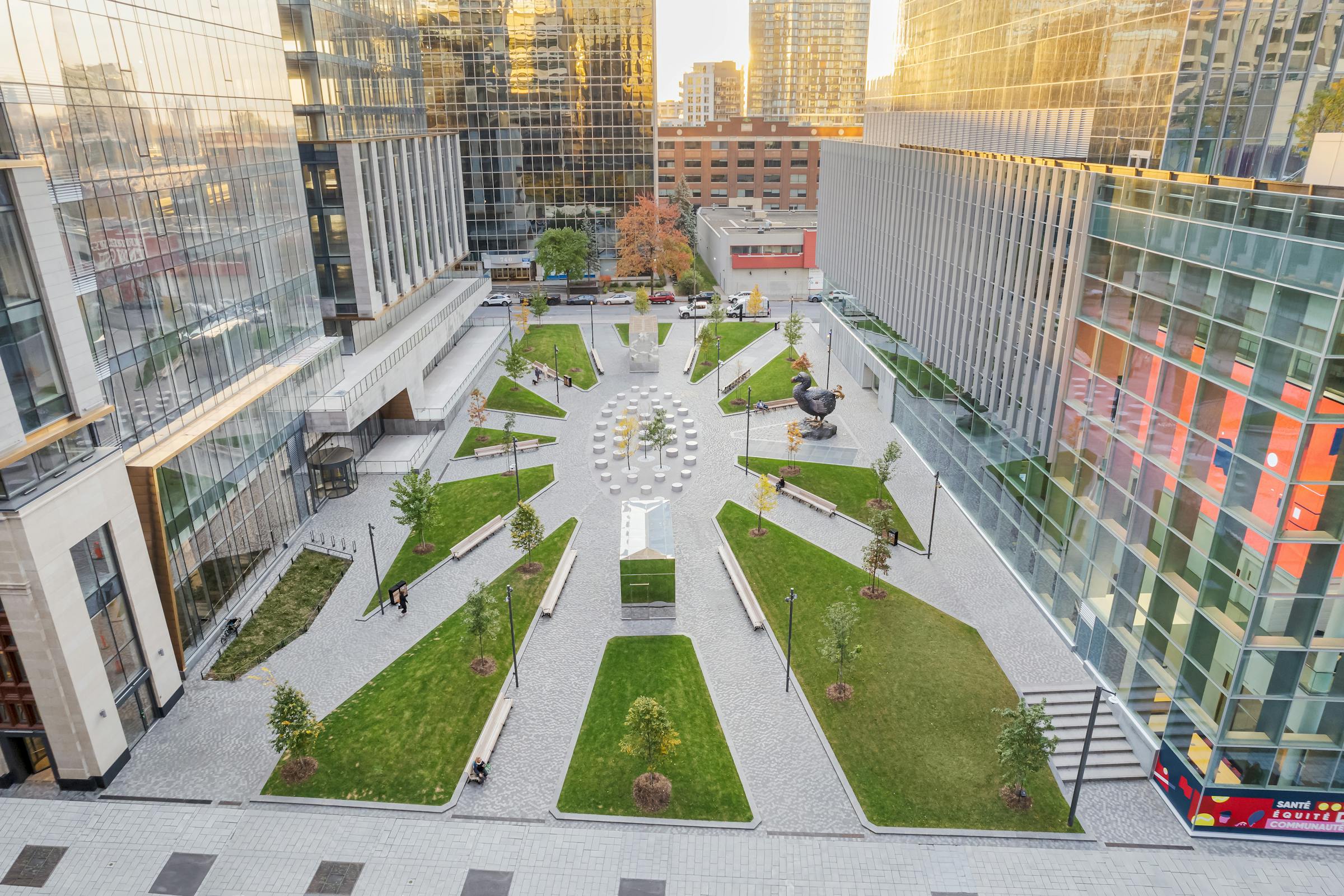 Vue aérienne d’un parc urbain symétrique planté de gazon et arbrisseaux, traversé de larges allées convergentes.