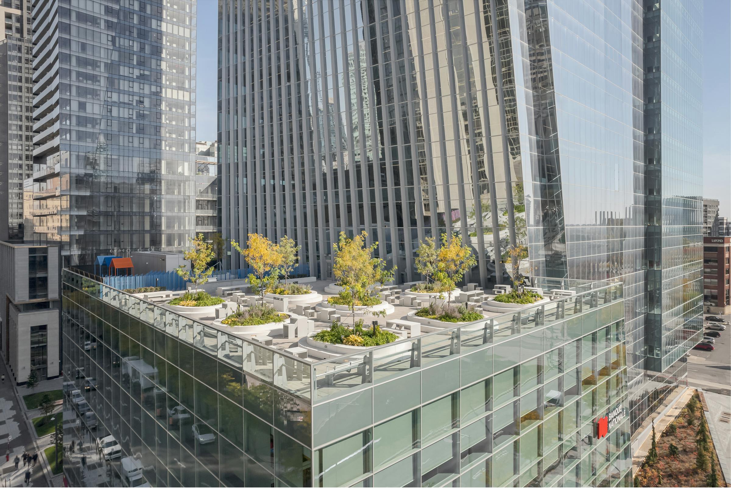 Aménagement paysager minimaliste sur la terrasse surélevée, encadré par des garde-corps vitrés et une vue dégagée.