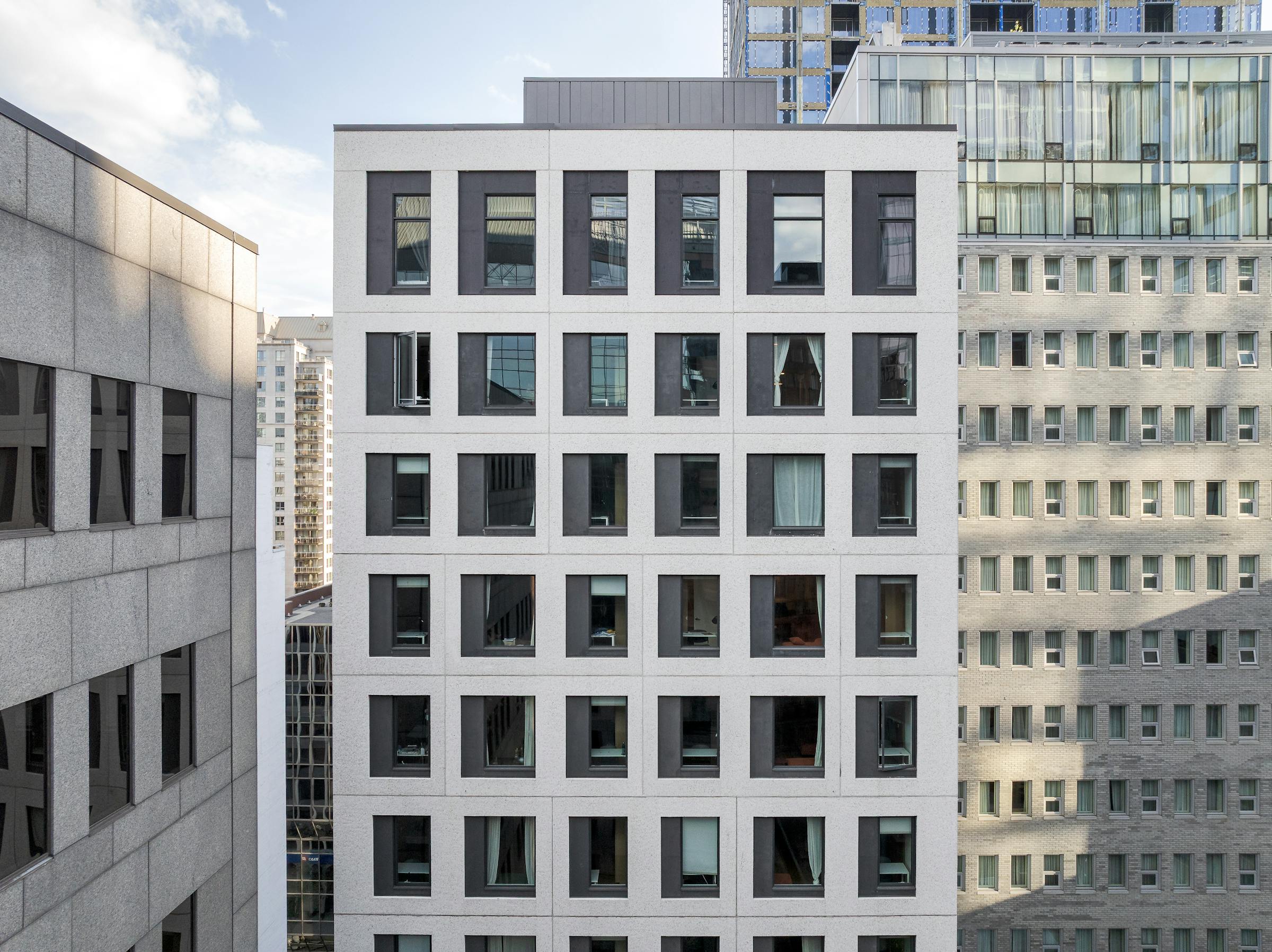 Composition symétrique illustrant la superposition de styles : pierre grise, cadres noirs et blanc cassé.