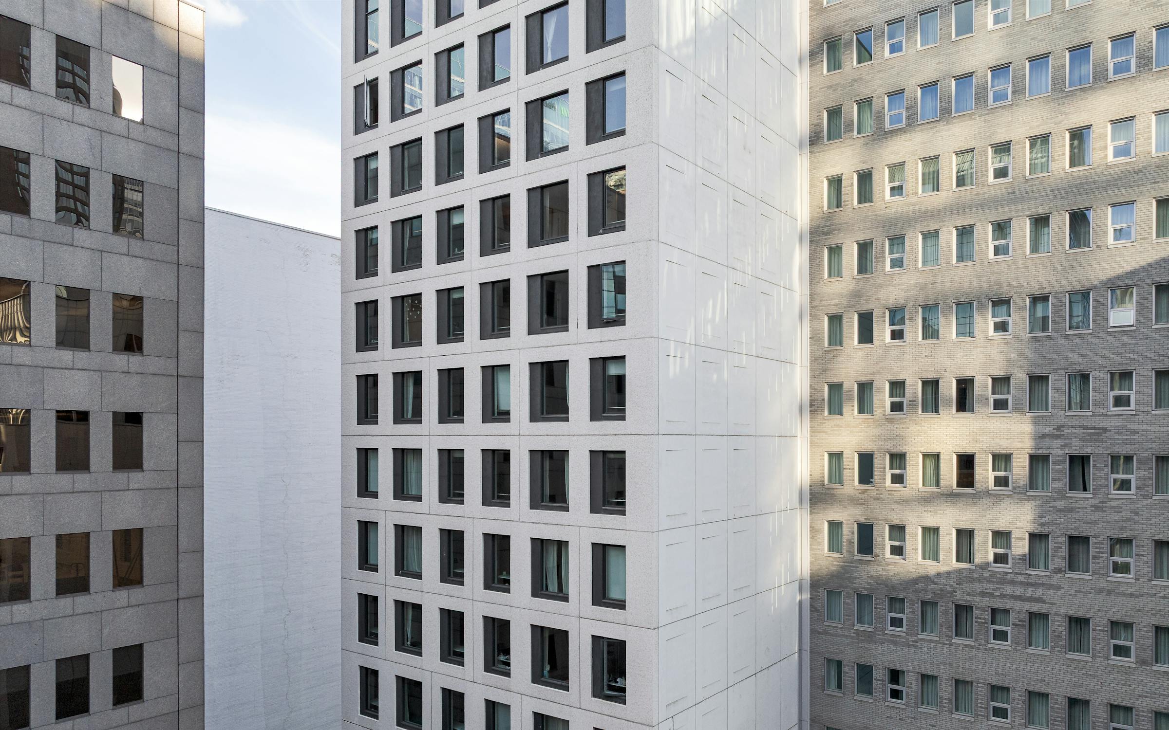 Contraste de textures entre l’enveloppe vitrée voisine et les surfaces mates du Palay.