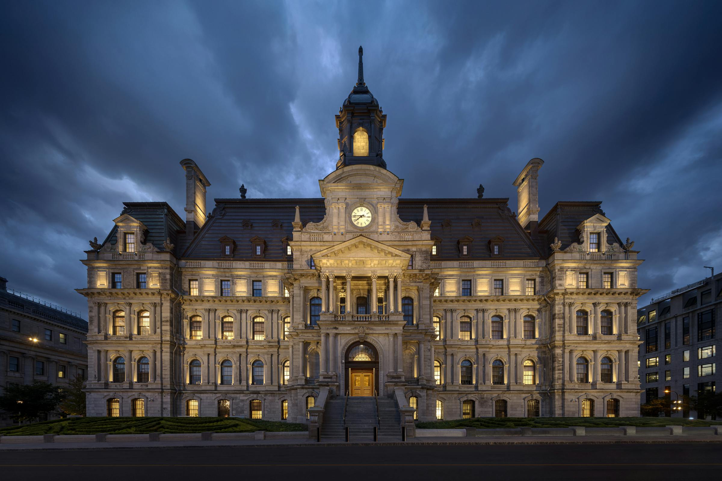 Vue nocturne de l’Hôtel de Ville de Montréal illuminé par un éclairage architectural dynamique.