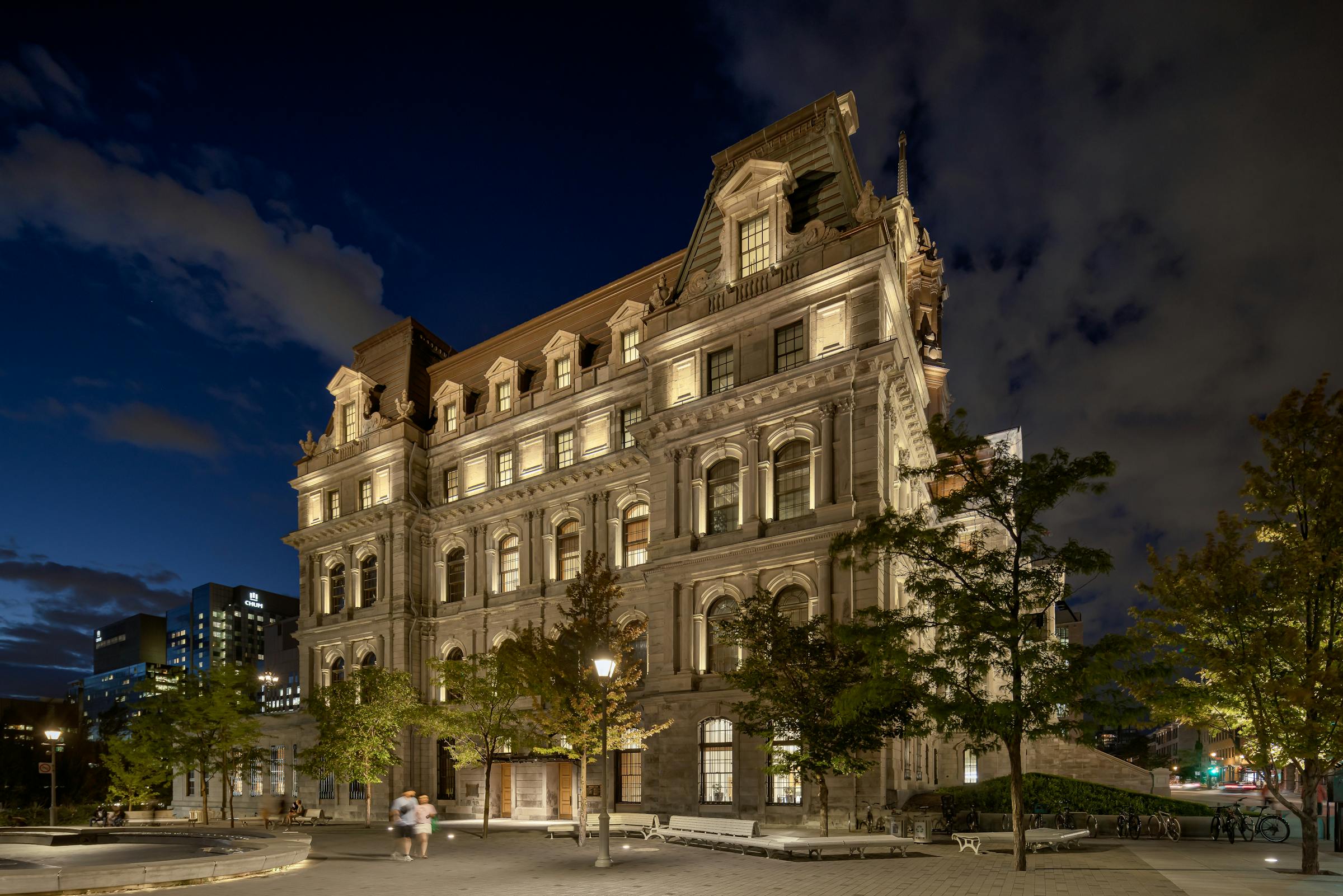 Vue à niveau de rue, captant la monumentalité du bâtiment illuminé.