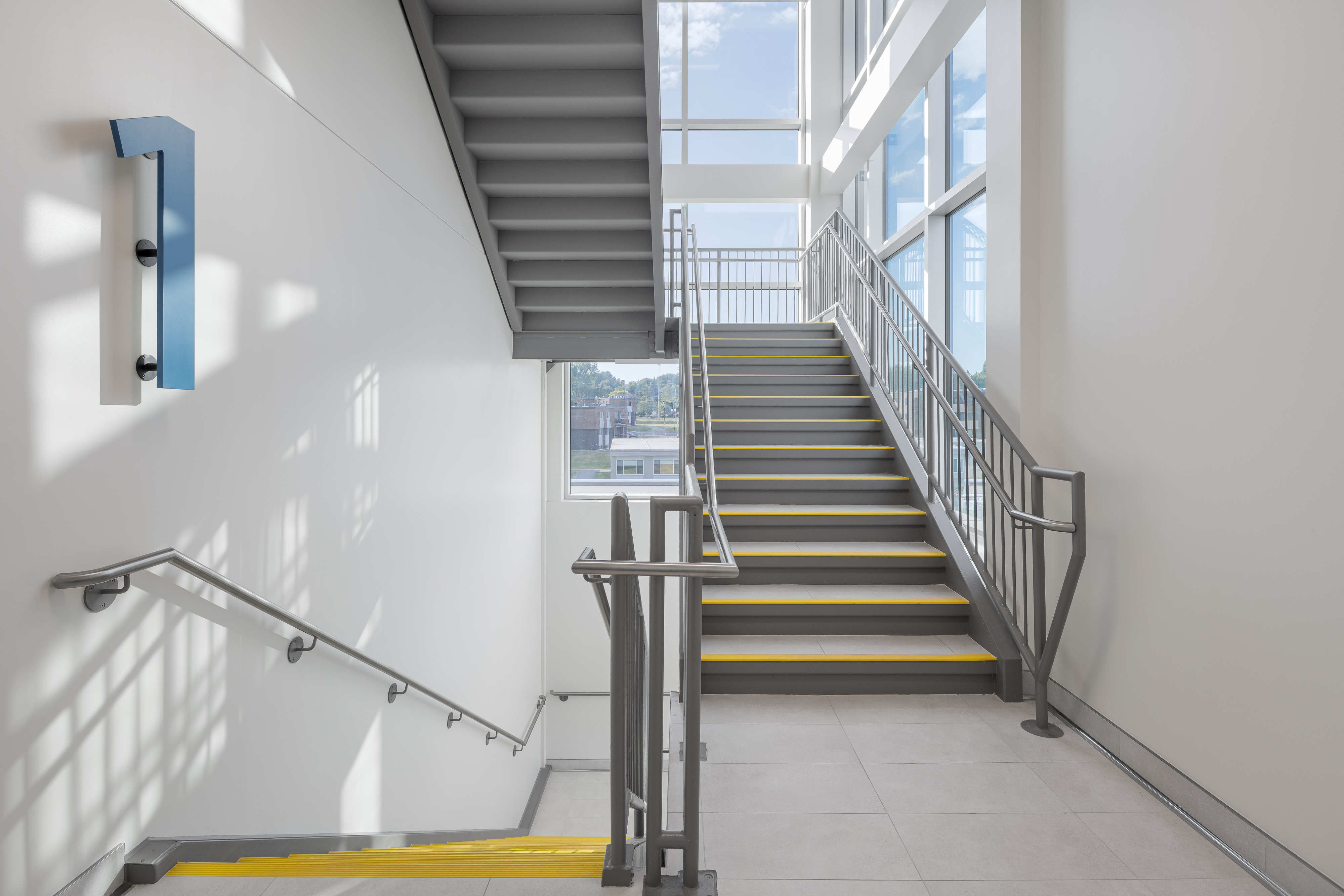 Escalier central inondé de lumière, symbole de fluidité et de mouvement.