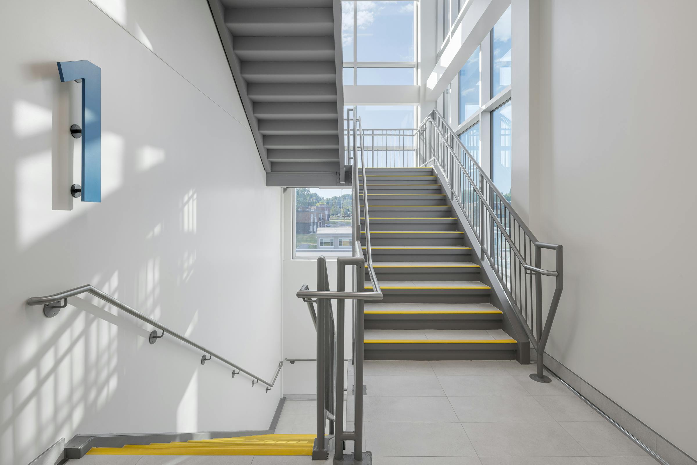 Escalier central inondé de lumière, symbole de fluidité et de mouvement.
