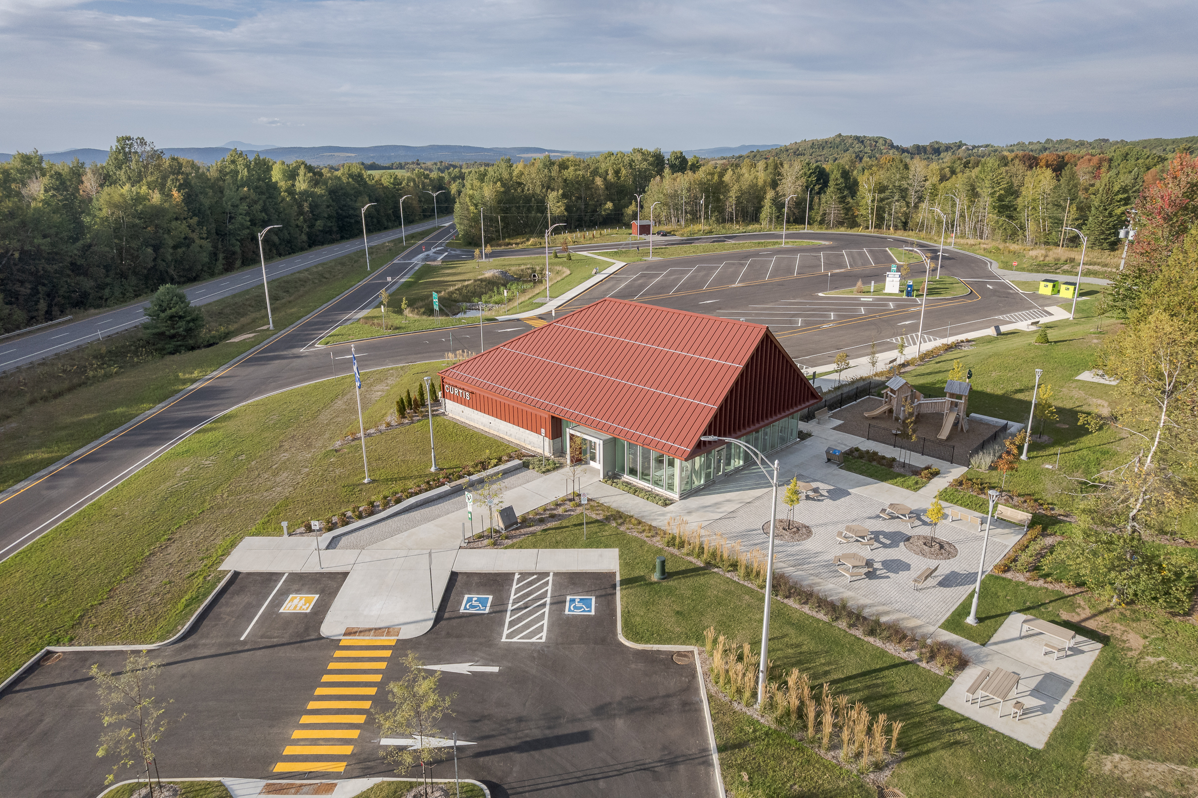Panoramic view of the Curtis rest area integrated into the hilly Eastern Townships landscape.
