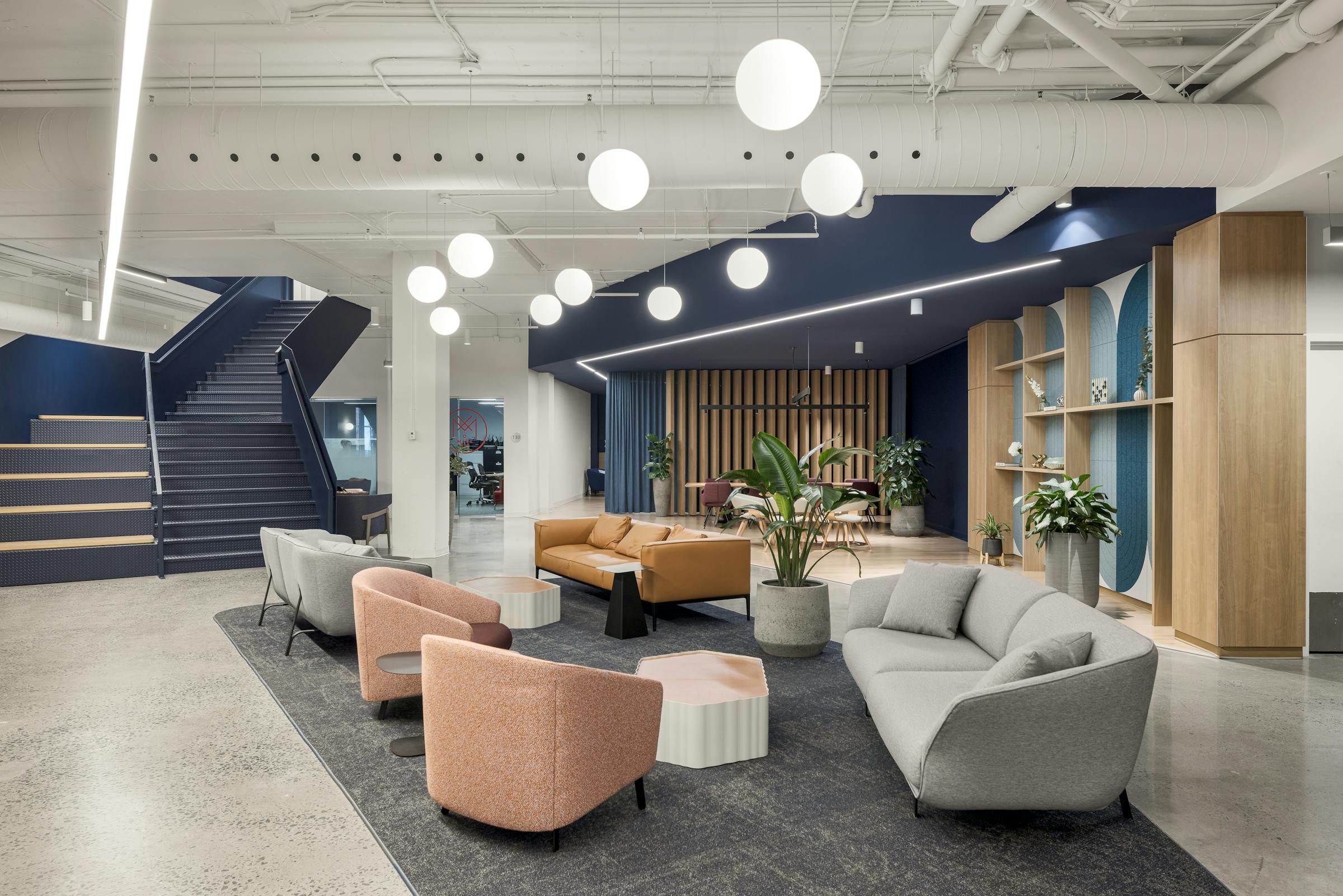 Photographie d’architecture d’un espace d’accueil lumineux avec luminaires suspendus et mobilier design.