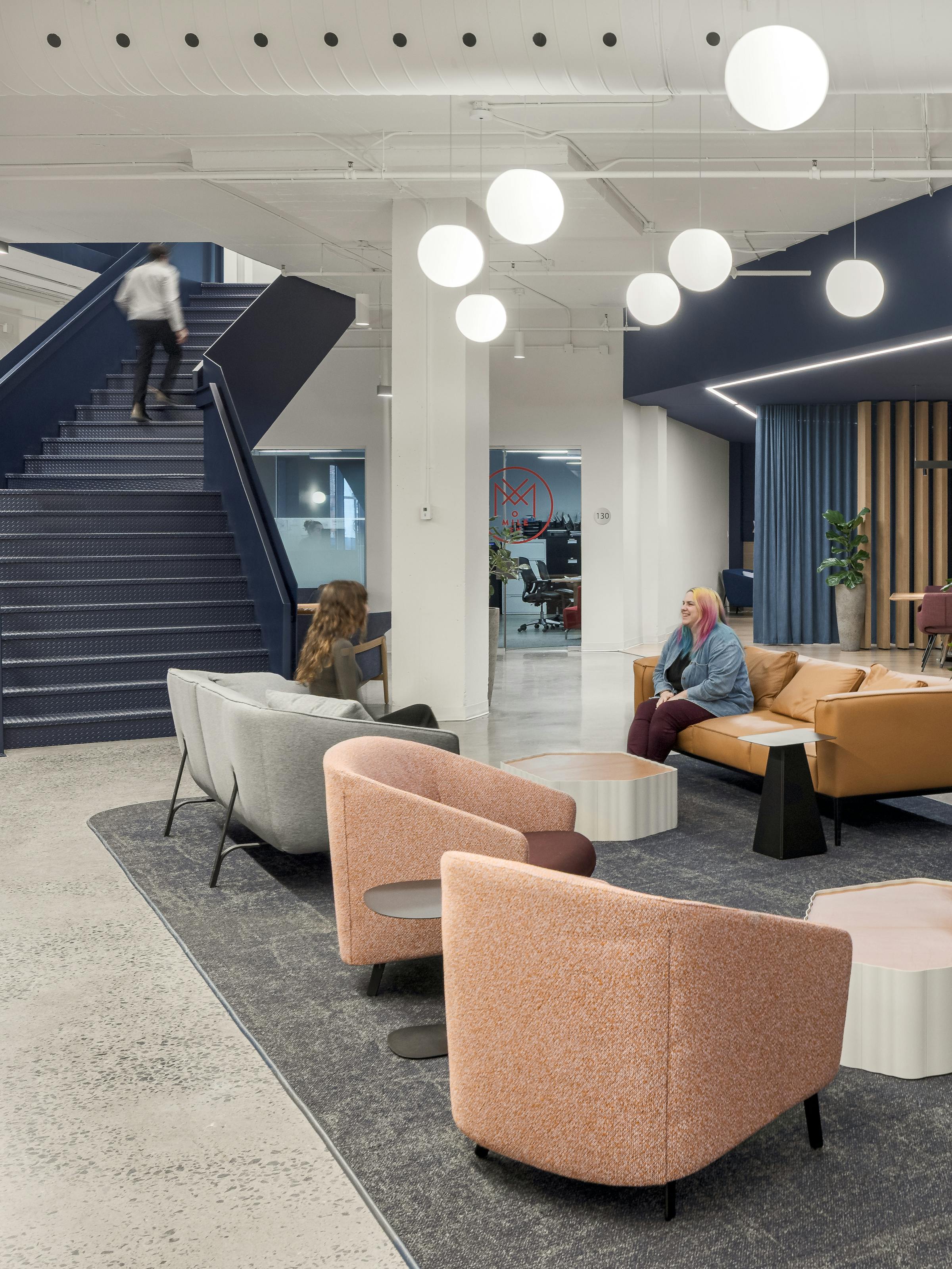 Photographie intérieure d’un hall contemporain avec escalier graphique et mobilier lounge.