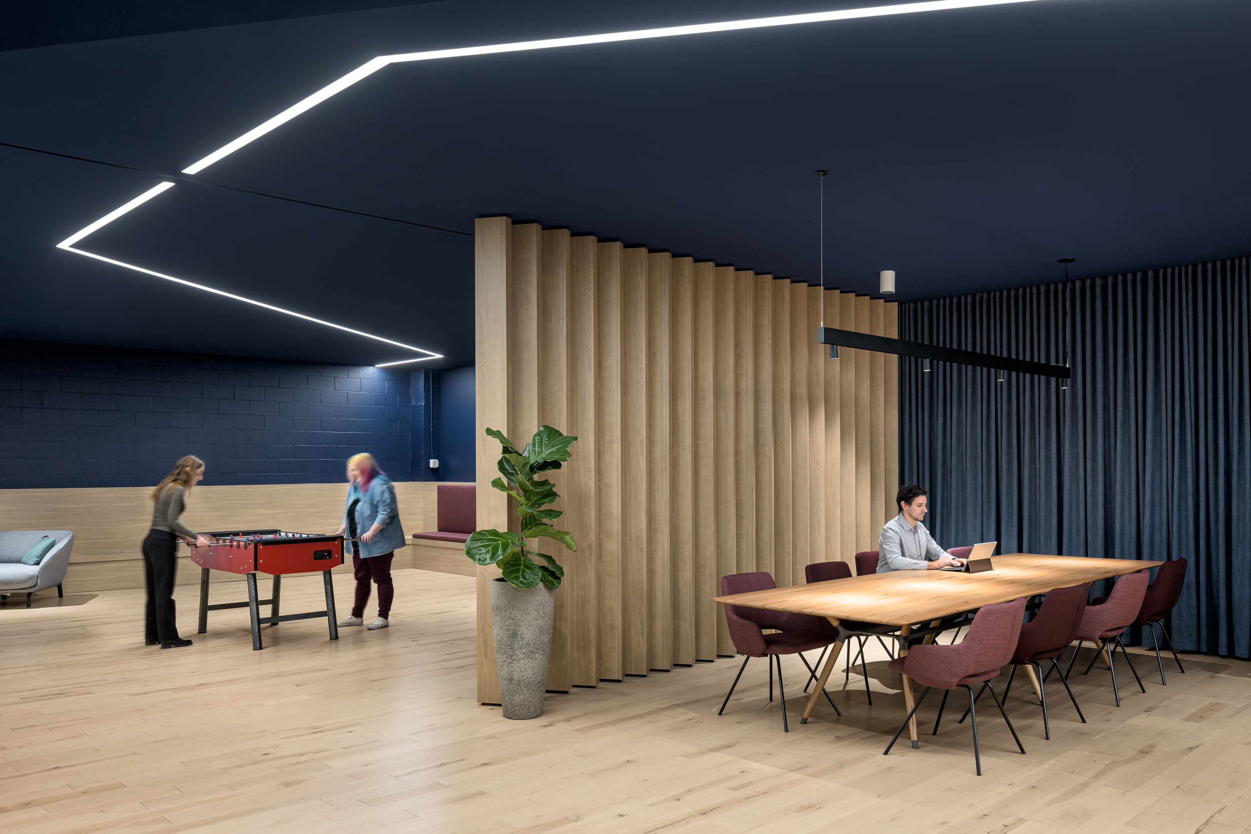 Photographie d’architecture d’un espace de travail collaboratif avec rideaux acoustiques et matériaux naturels.