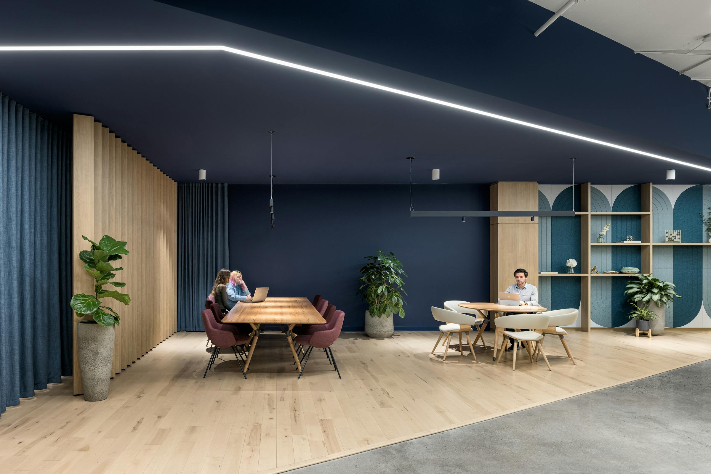 Photographie d’un espace social avec table commune, éclairage architectural et ambiance chaleureuse.