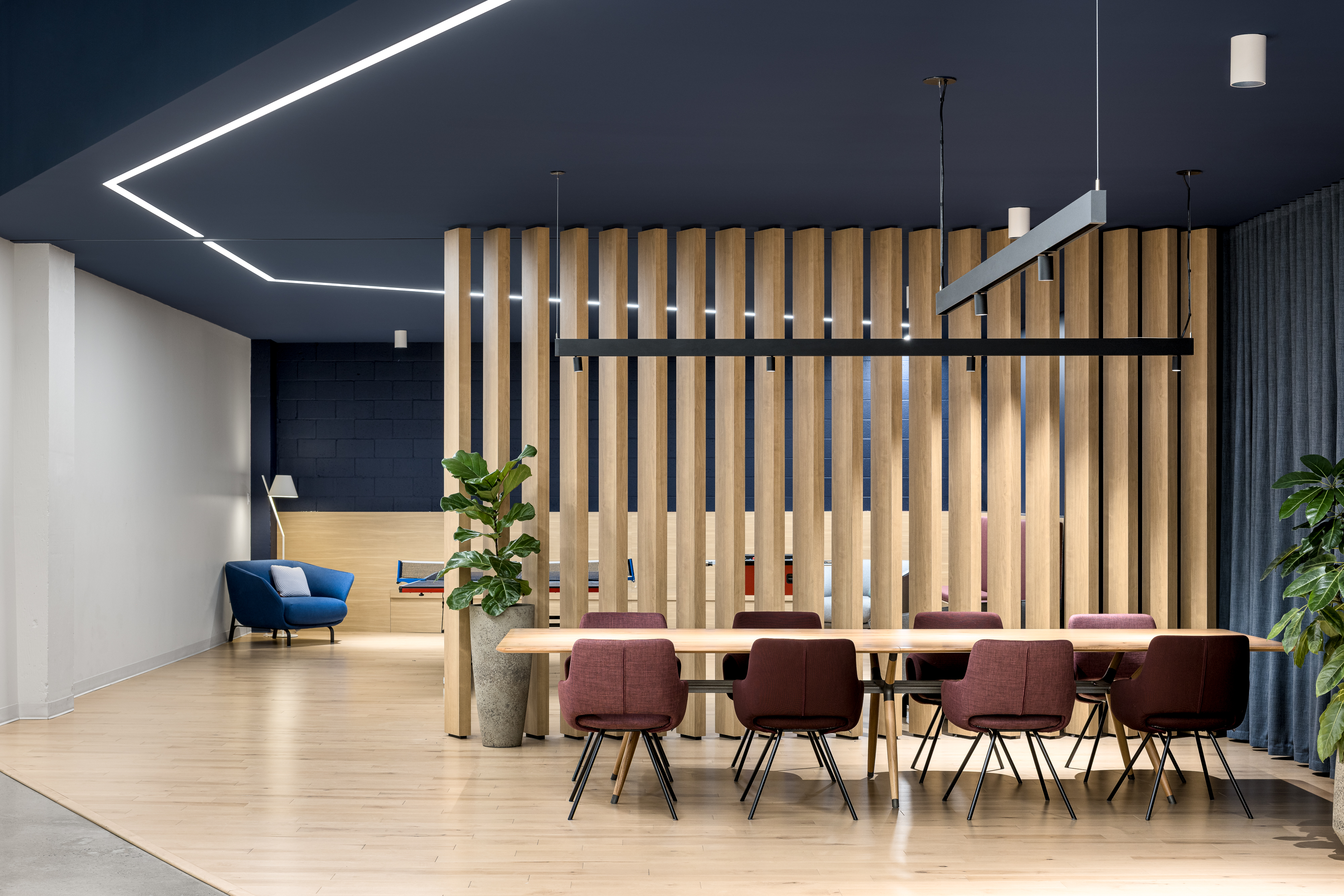 Photographie intérieure d’un espace de réunion informel avec cloison en lattes de bois et design contemporain.