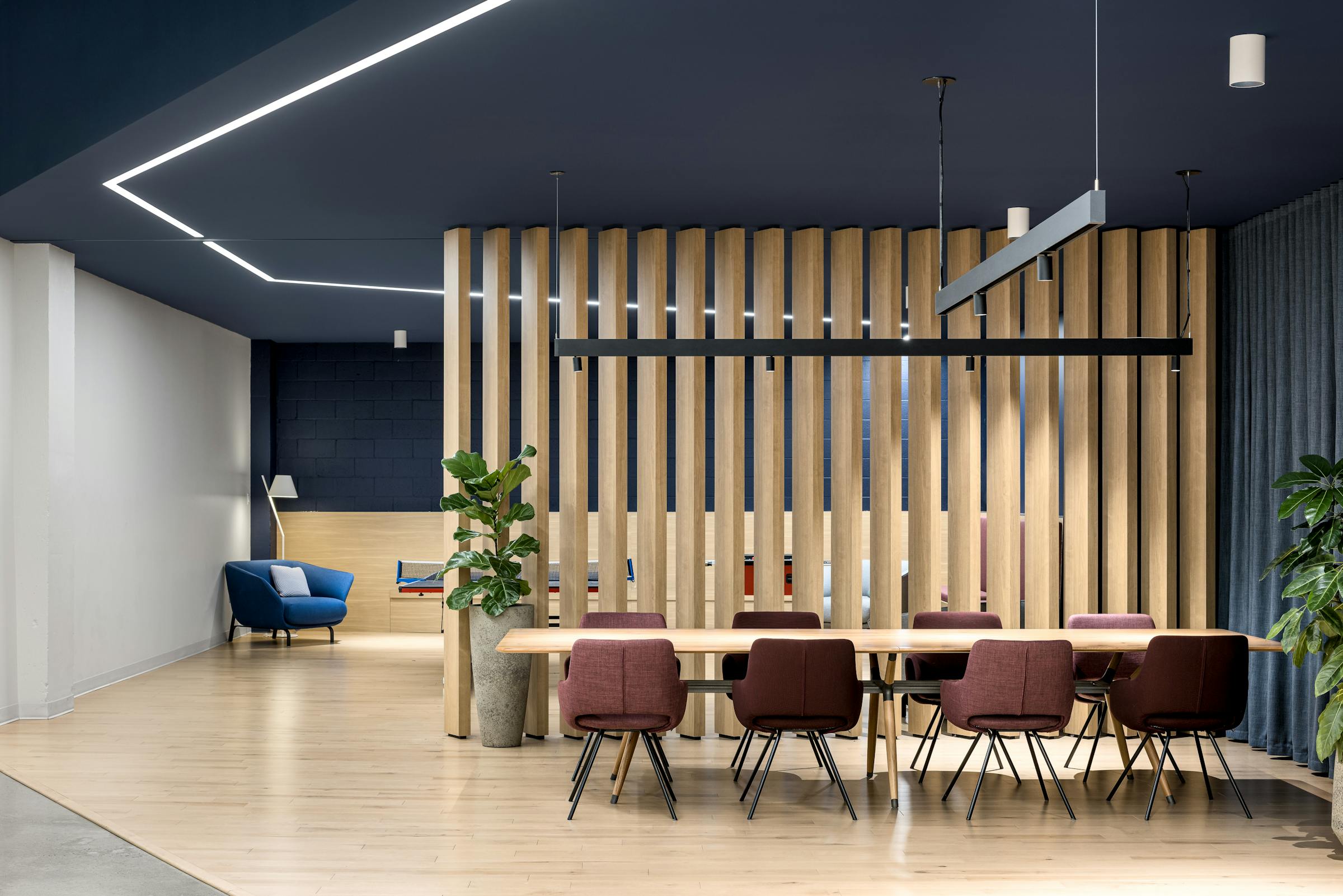 Photographie intérieure d’un espace de réunion informel avec cloison en lattes de bois et design contemporain.