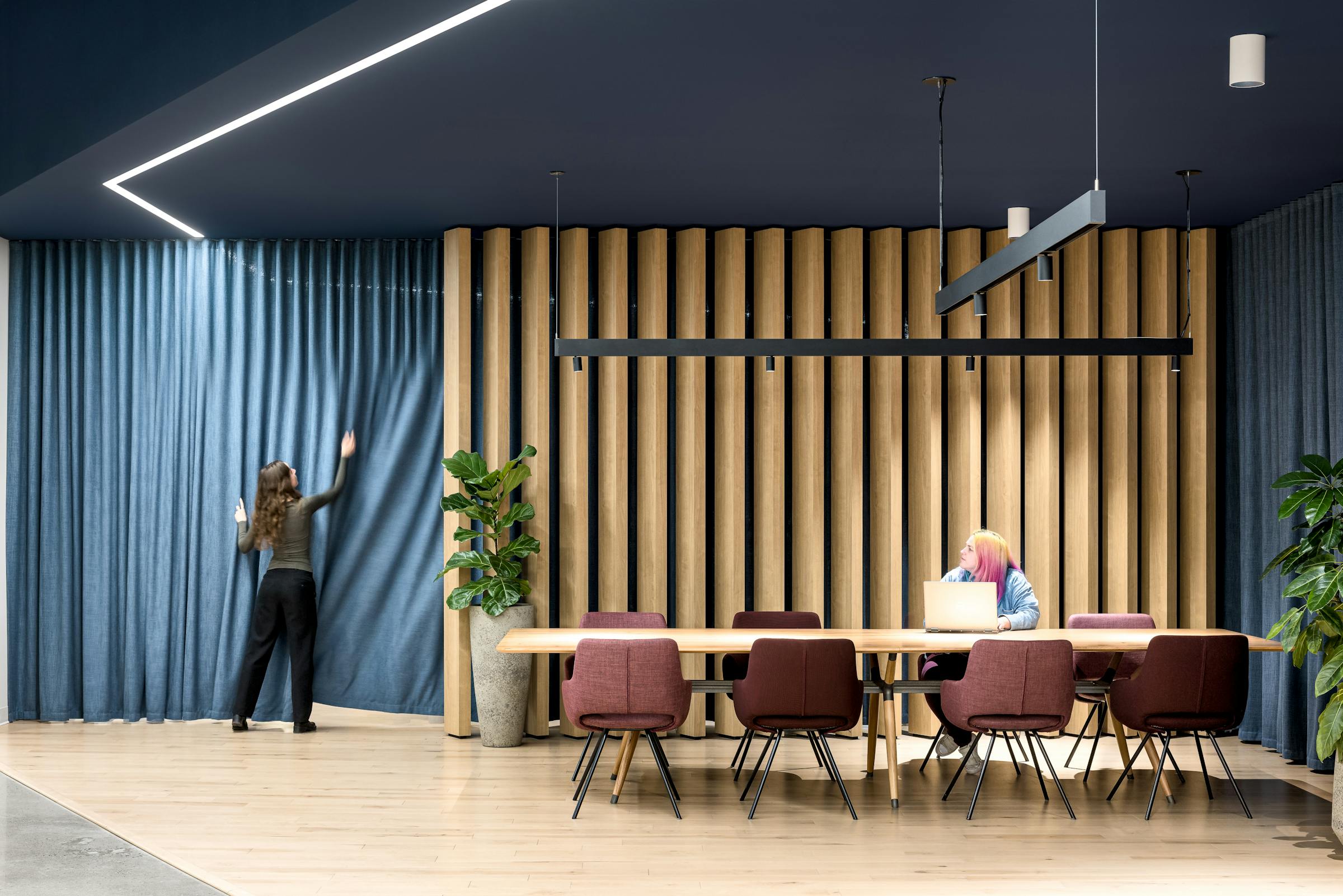 Photographie d’architecture d’une salle collaborative avec plafond lumineux géométrique et mobilier moderne.