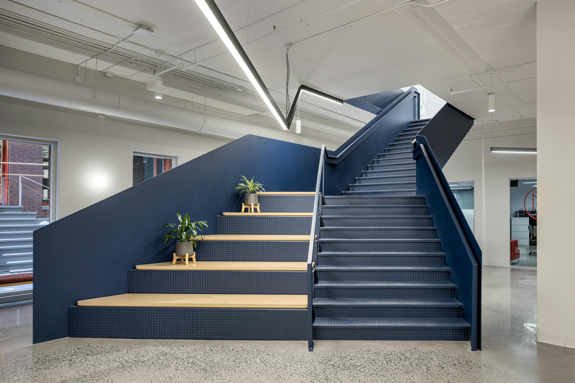 Photographie d’un espace de coworking contemporain avec mobilier design et éclairage linéaire intégré.