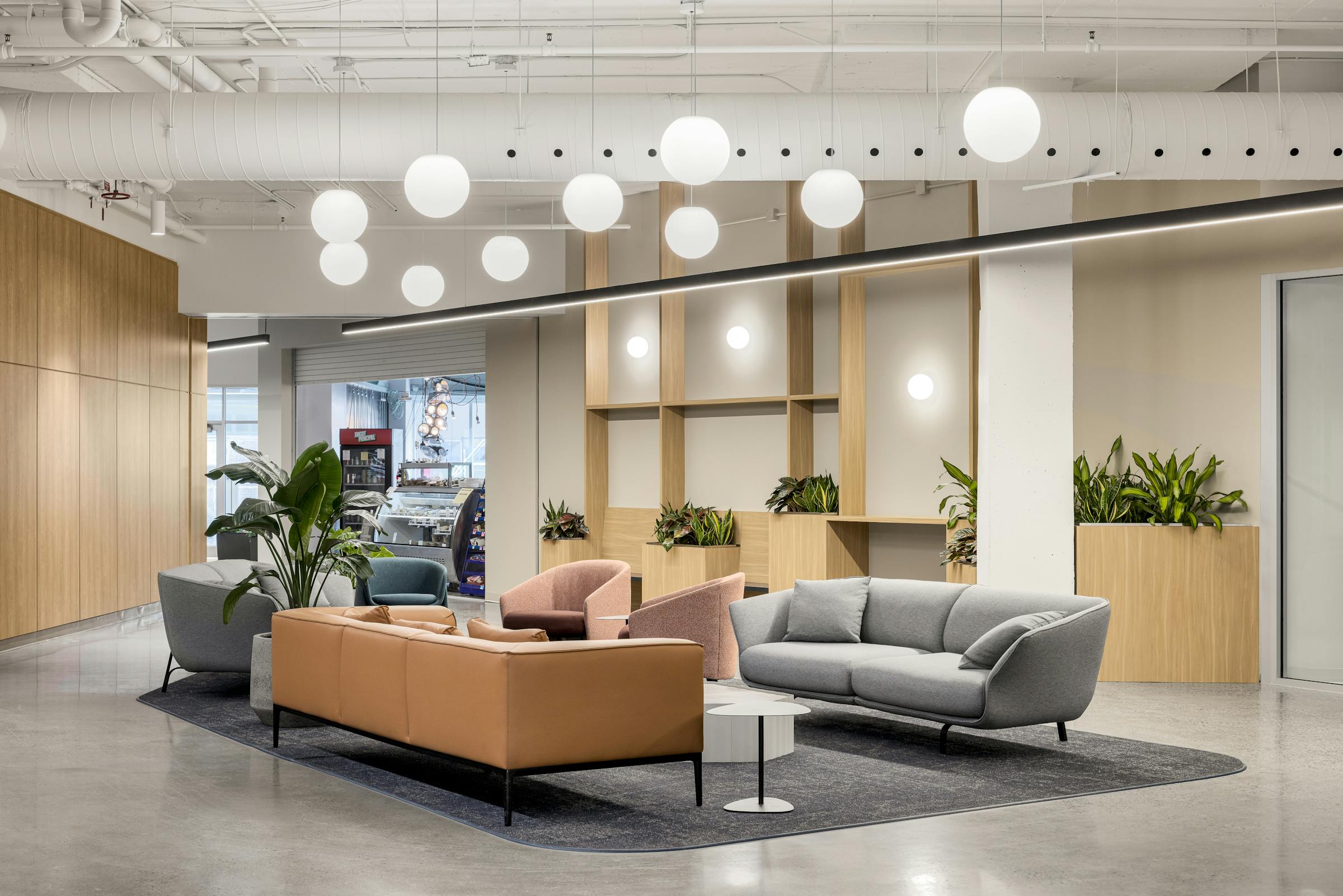 Photographie d’architecture d’un espace commun avec escalier central, luminaires suspendus et aménagement contemporain.