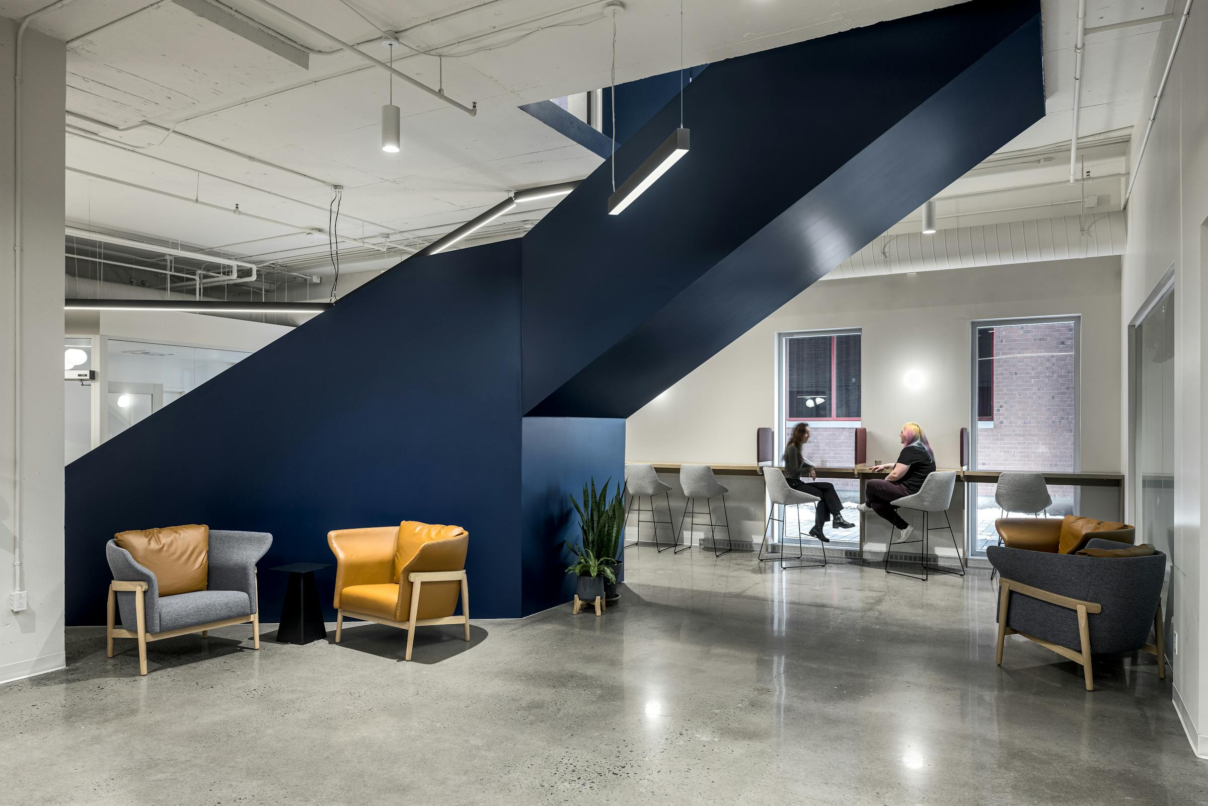 Photographie d’architecture d’un espace lounge contemporain avec escalier bleu sculptural et mobilier design.