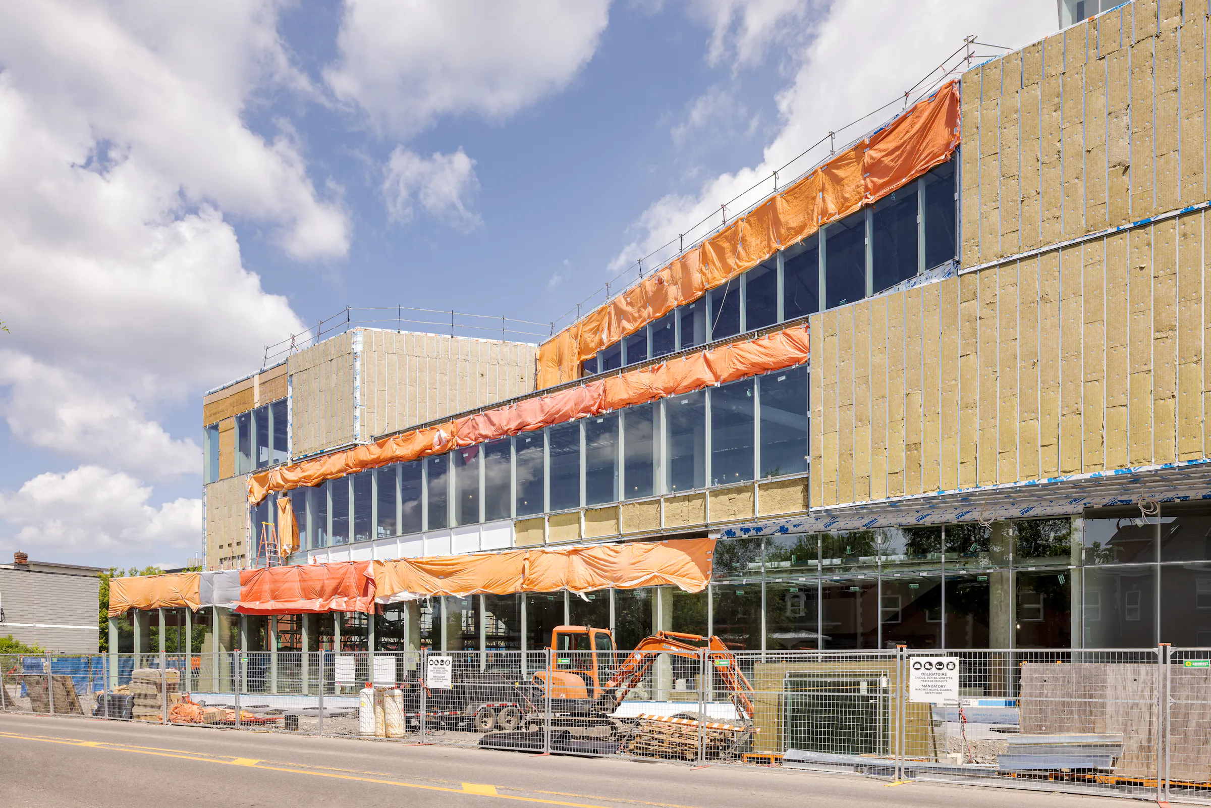 Vue latérale du bâtiment avec pare-air apparent et sections de façade partiellement vitrées.