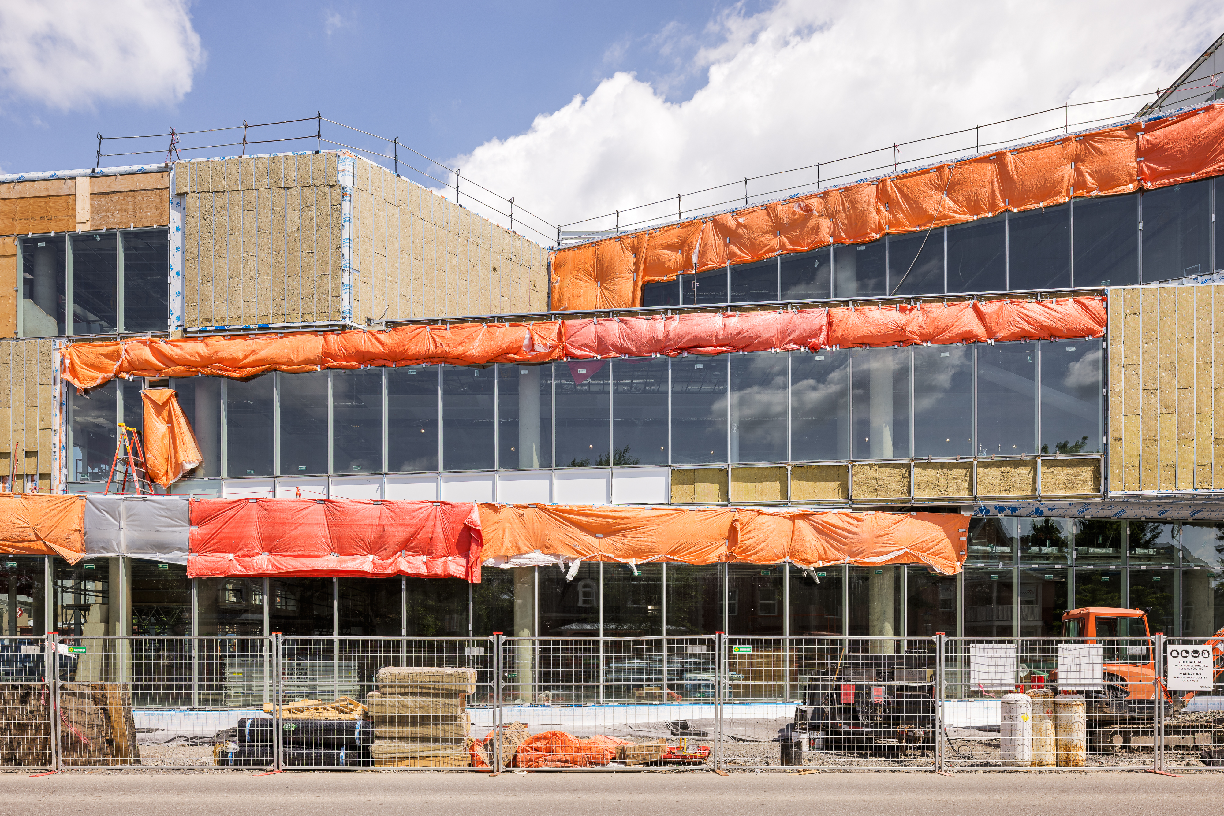 Façade principale en cours de construction avec installation du revêtement en terra cotta et grandes surfaces vitrées.