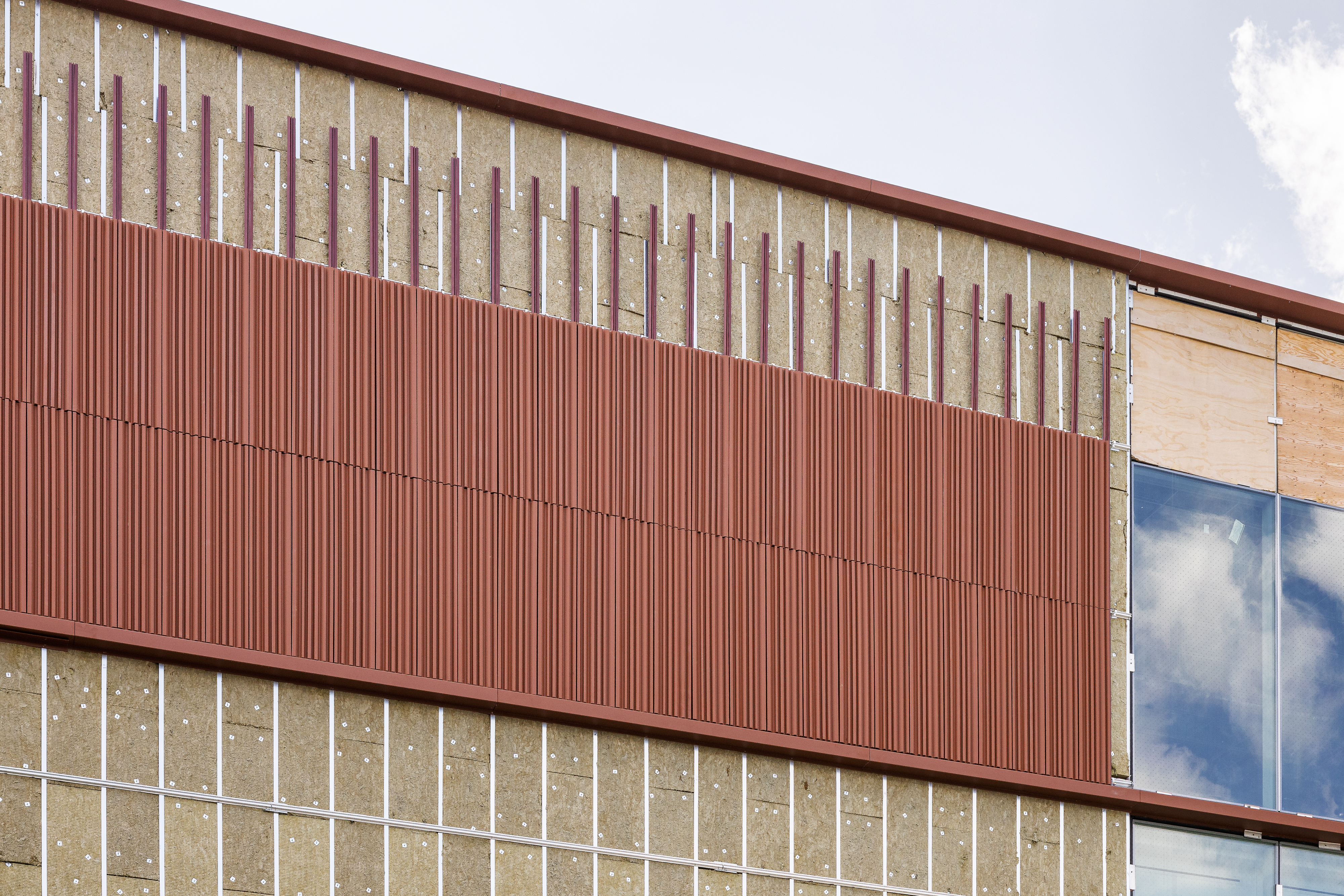 Détail de façade avec alternance de panneaux opaques et surfaces vitrées.