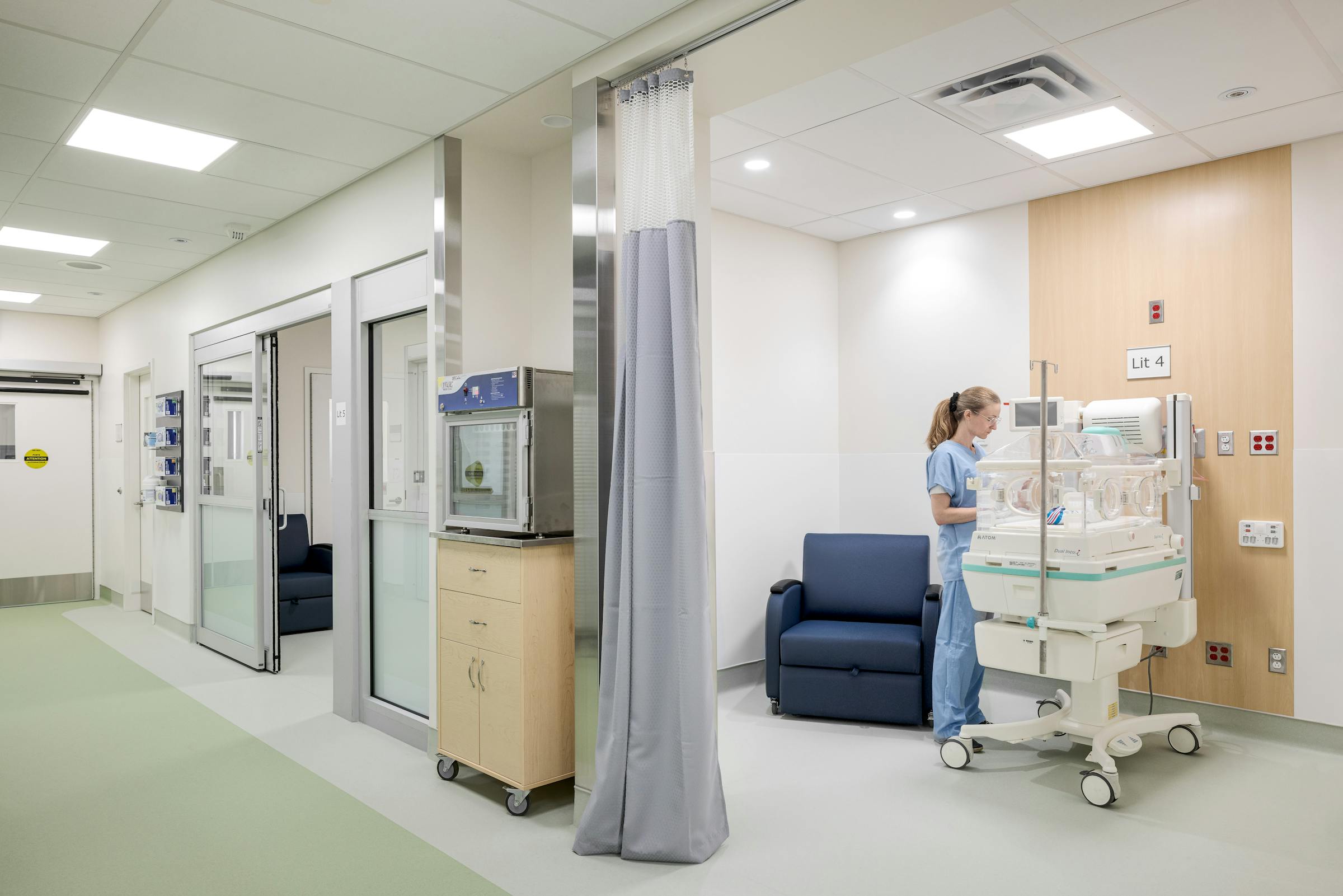 Unité de soins hospitalière avec berceau médical et espace famille, documentée en photographie d’architecture.