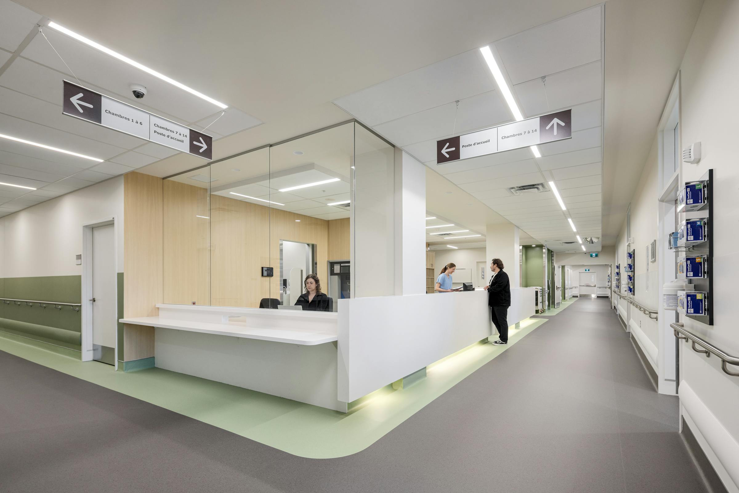 Poste infirmier central en hôpital avec comptoir blanc et éclairage intégré, photographie d’architecture intérieure.