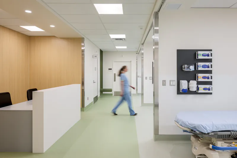 Zone de soins hospitalière avec circulation ouverte et matériaux durables, captée en photographie d’architecture.