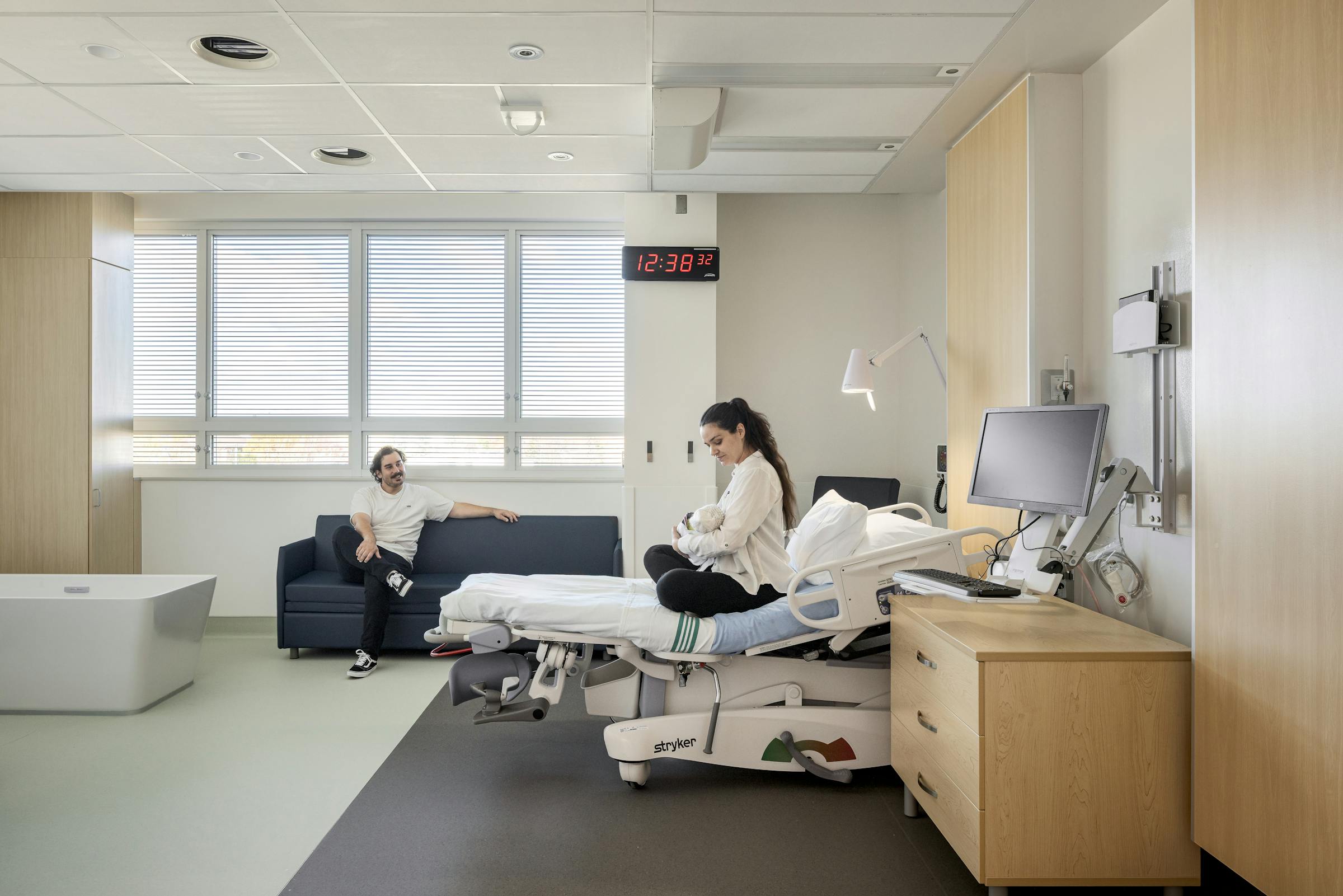 Chambre de clinique hospitalière moderne avec équipement médical et lumière naturelle, en photographie d’architecture.