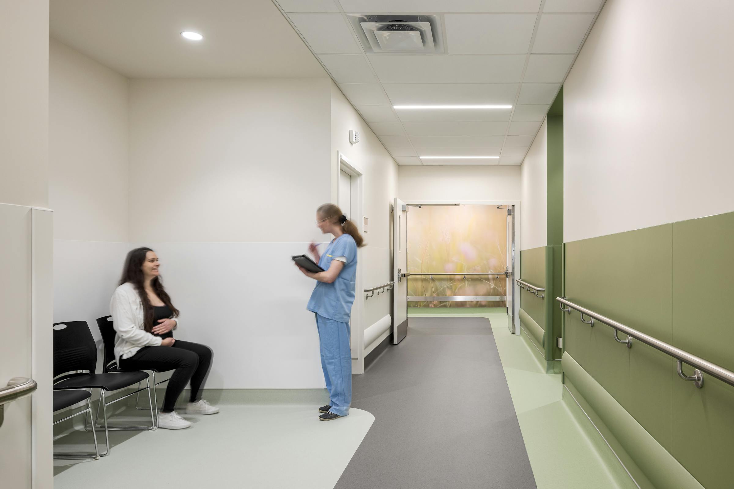 Espace d’attente en hôpital intégré à un couloir clinique, mis en valeur par une photographie architecturale.