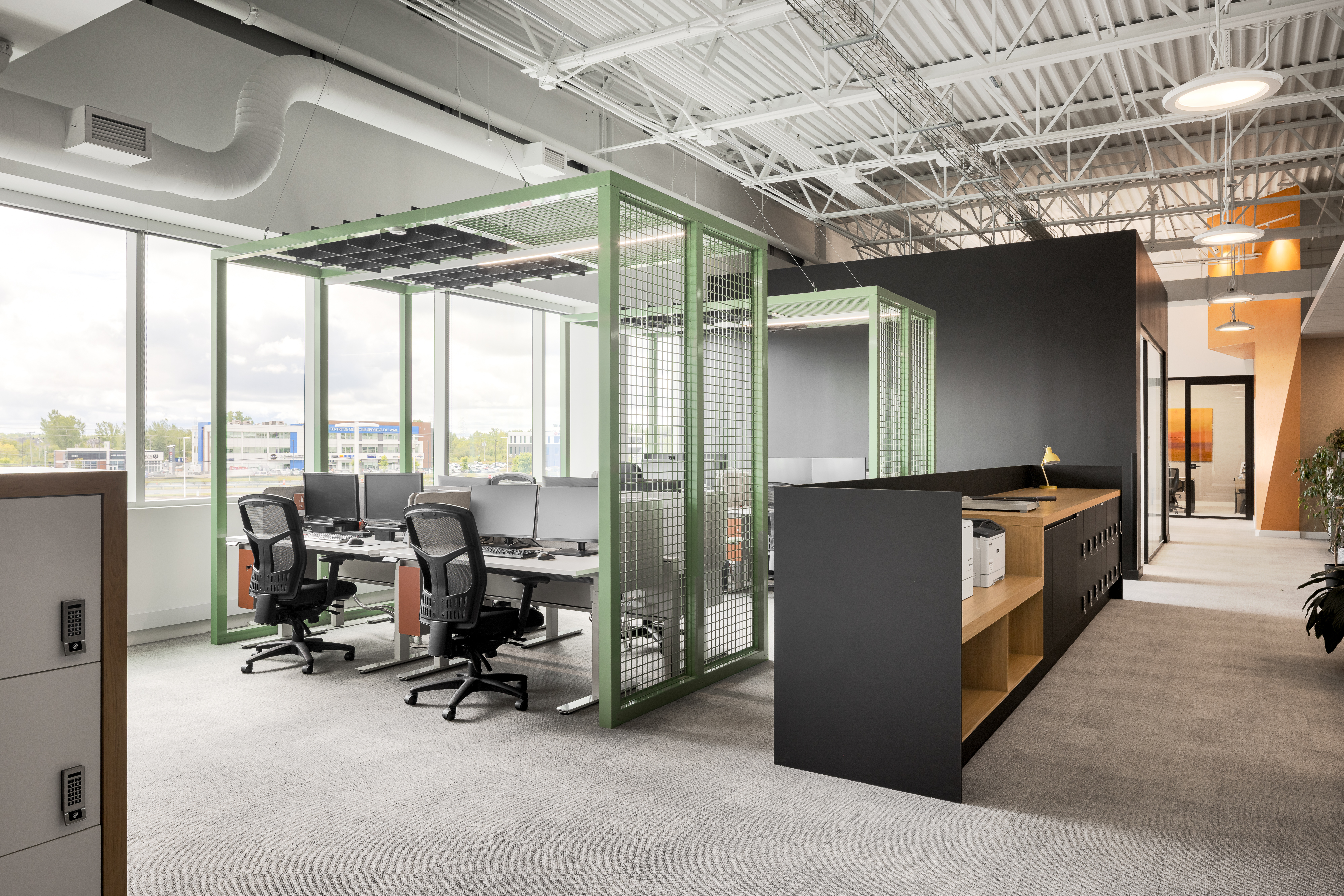 Photographie d’architecture d’un open space lumineux avec postes de travail, structure apparente et design de bureaux modernes.