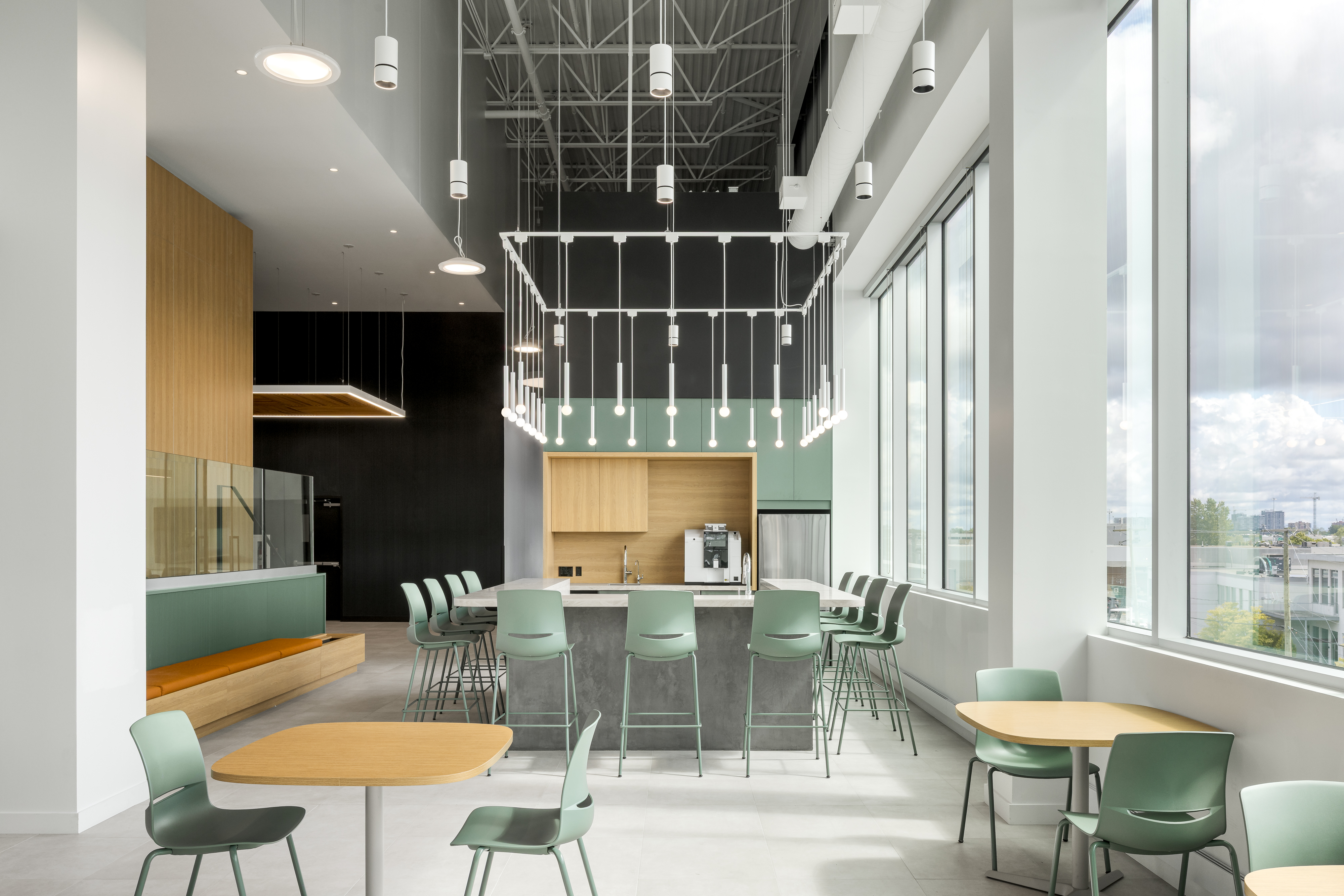 Photographie d’architecture d’un espace détente de bureaux avec grandes fenêtres, mobilier design et lumière naturelle.