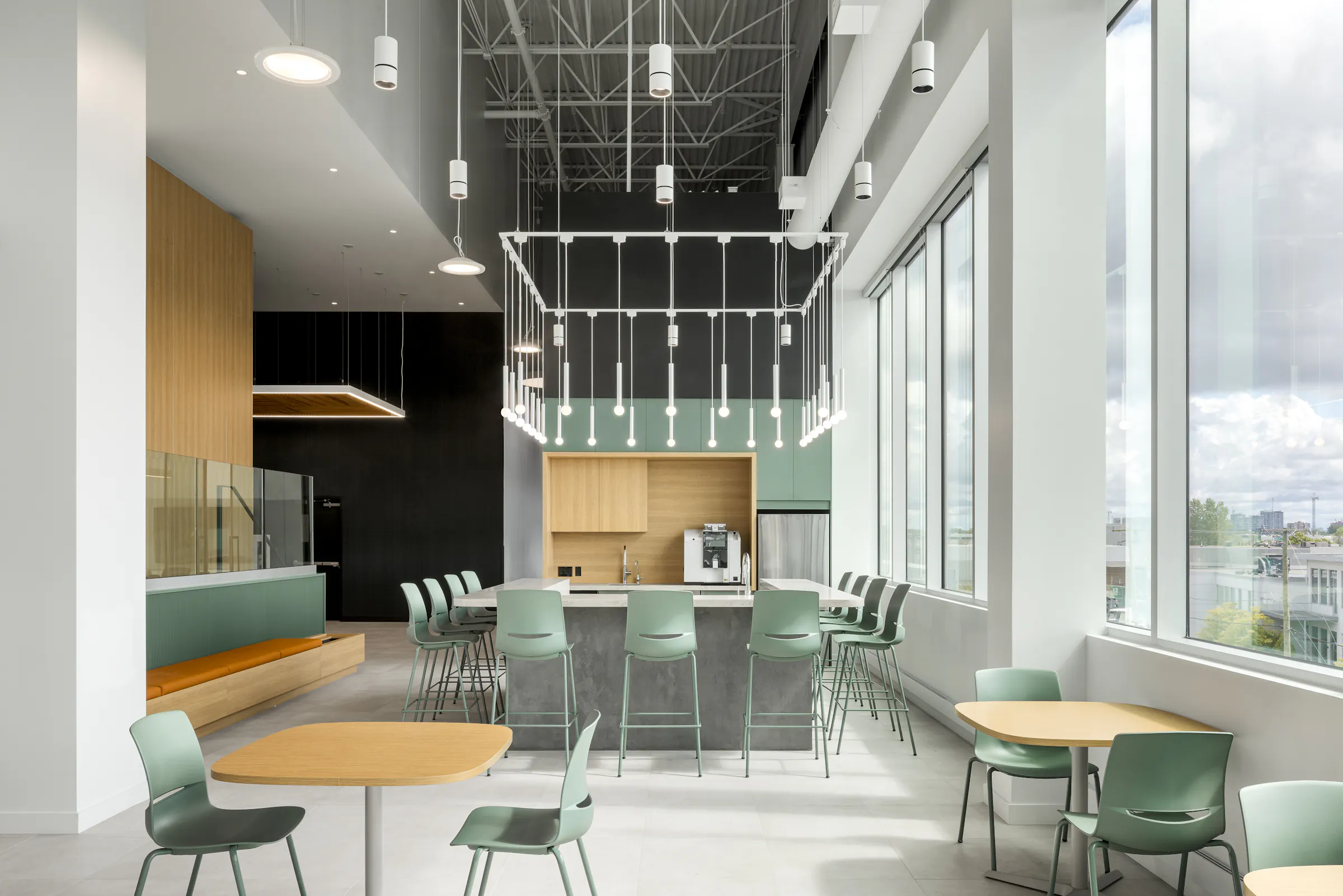 Photographie d’architecture d’un espace détente de bureaux avec grandes fenêtres, mobilier design et lumière naturelle.