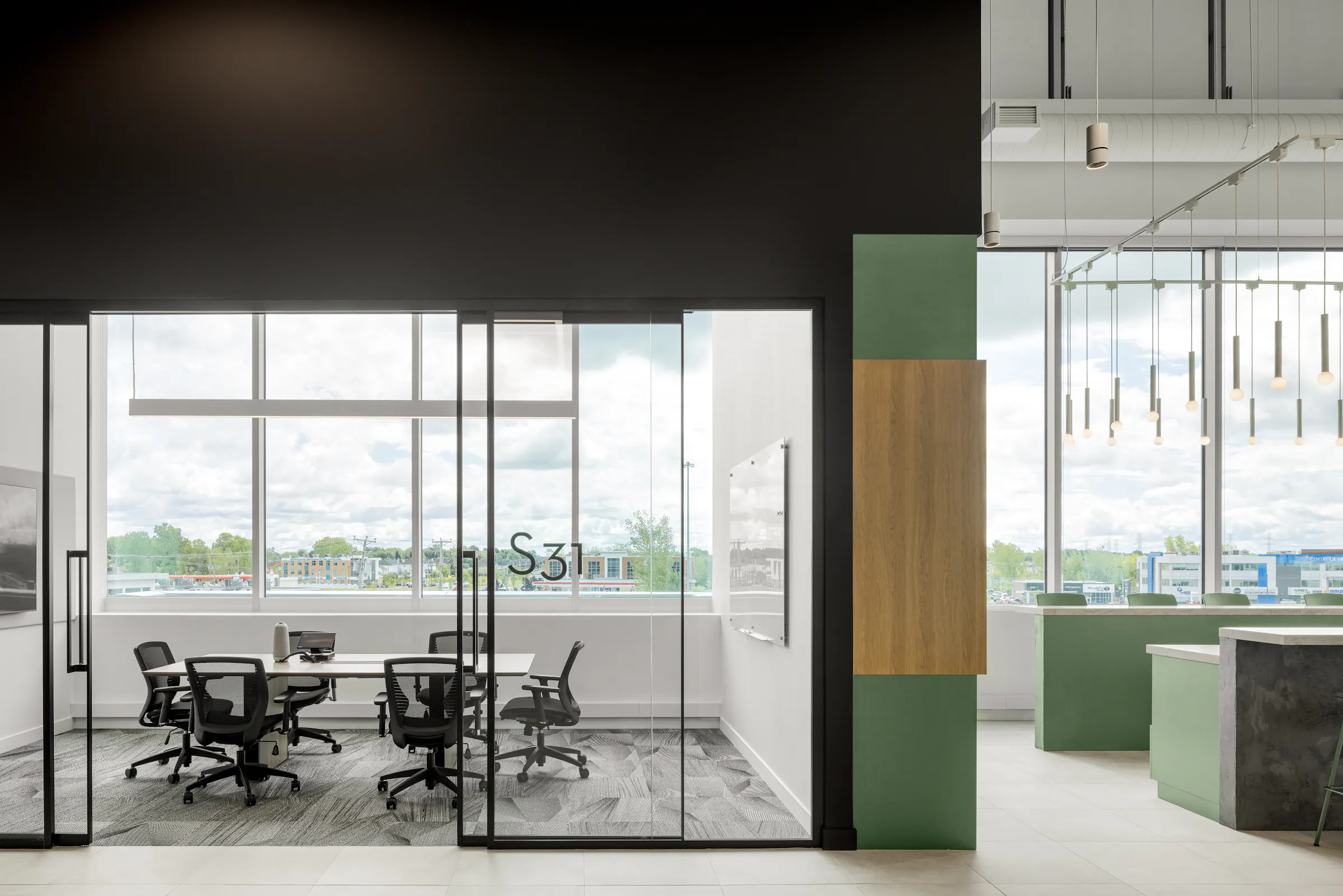 Photographie d’architecture d’une salle de réunion vitrée avec vue extérieure et design intérieur de bureaux contemporains.