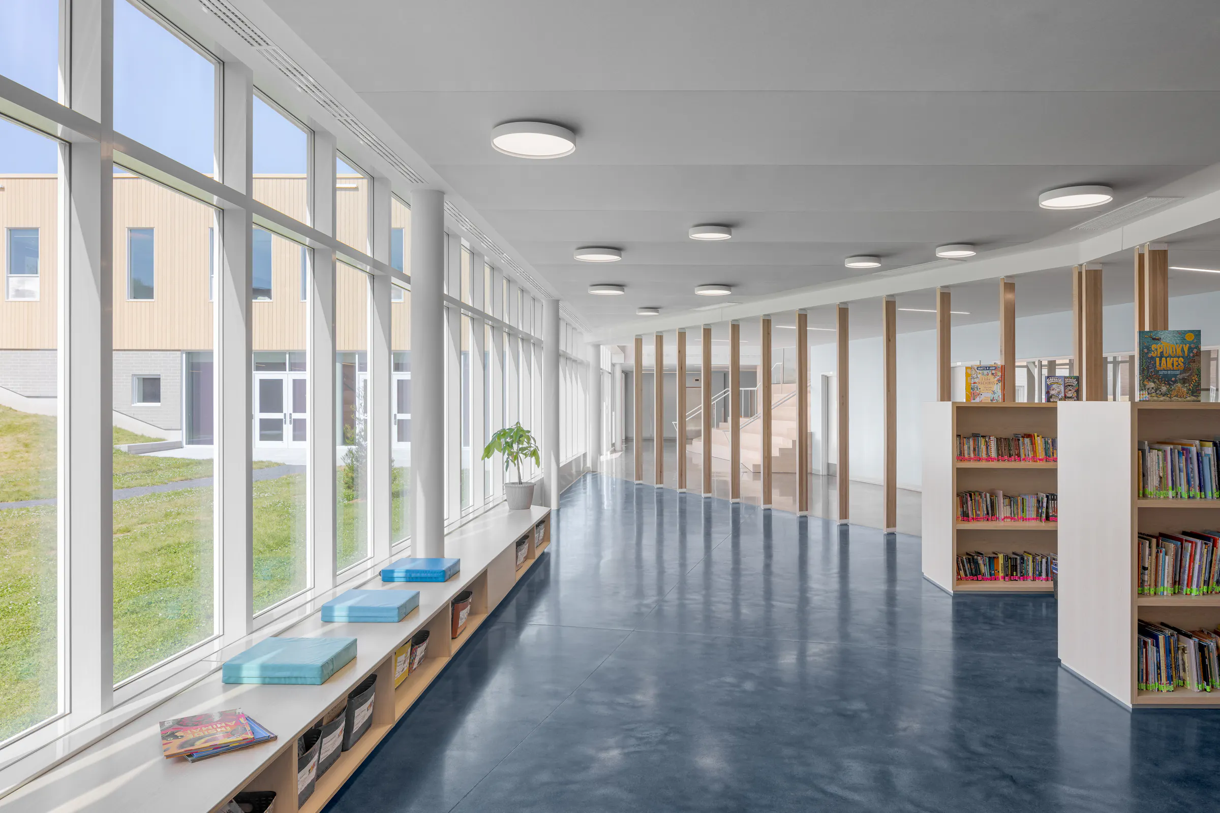 Photographie d’architecture d’un corridor scolaire lumineux avec façade vitrée et design intérieur contemporain d’école primaire.